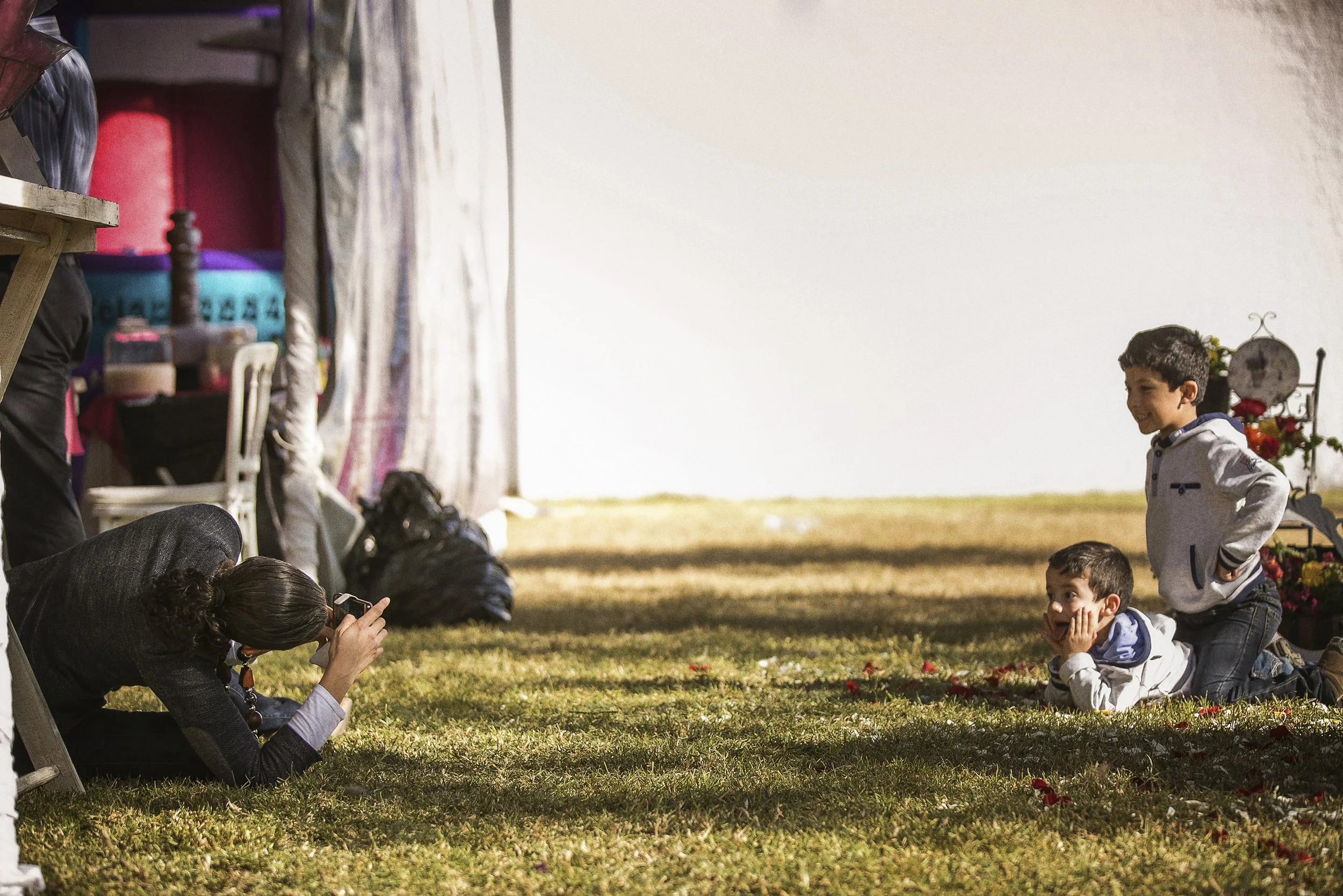 Fotografía documental de niño agachado en jardín mientras observa la celebración.