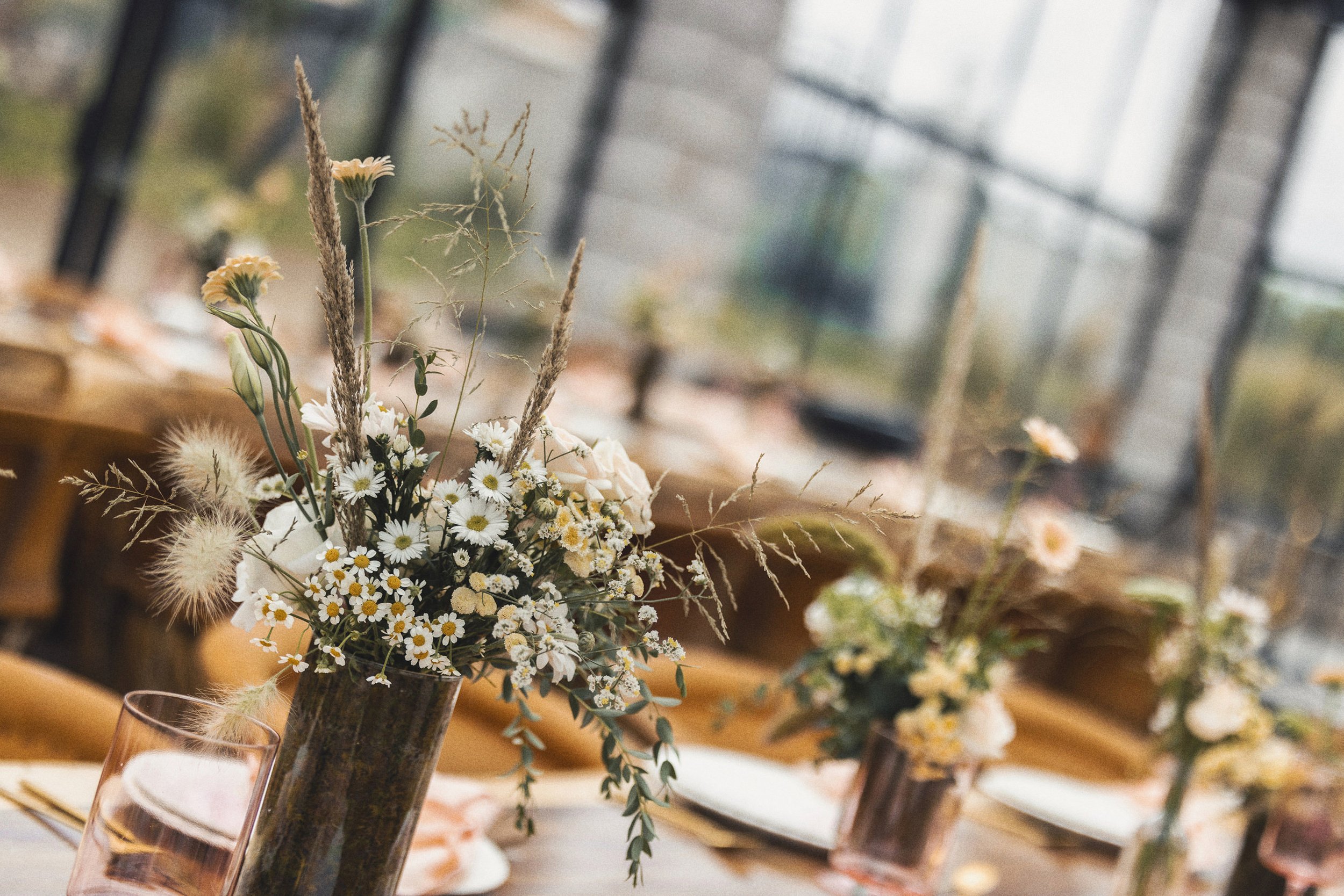 Fotografía de arreglos florales sobre mesas, luz natural y ambiente previo a la ceremonia.