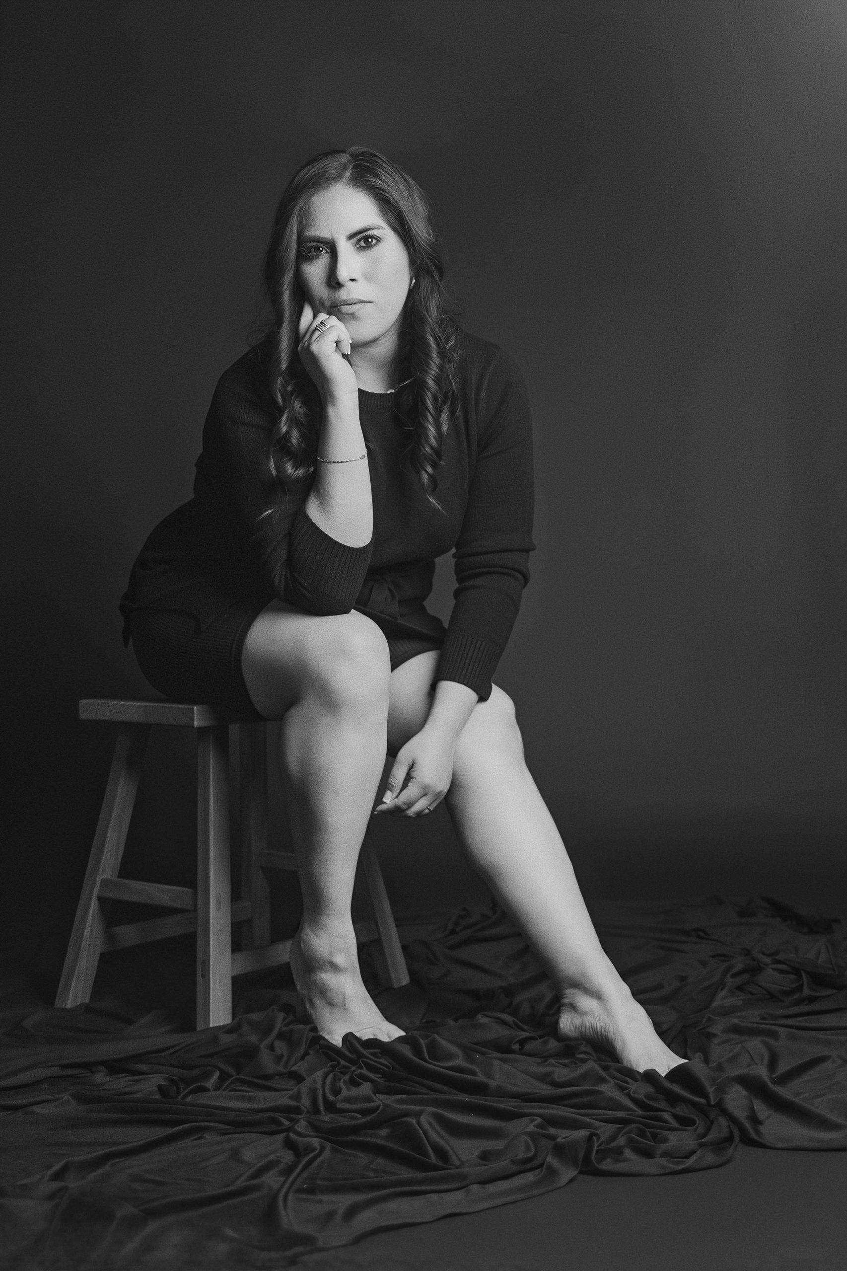 Retrato en blanco y negro de mujer sentada en banco, mirada directa y expresión firme.