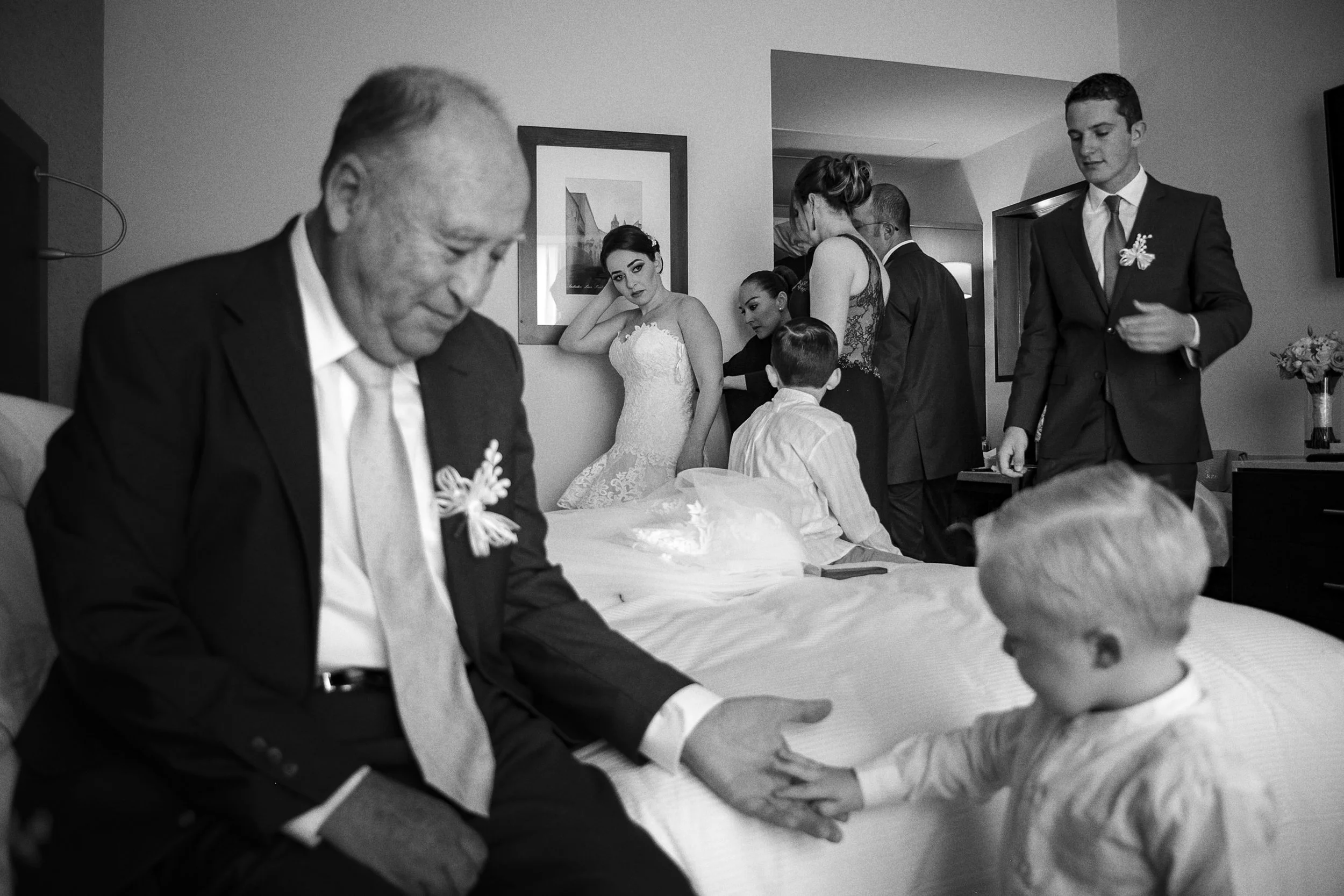 Fotografía en blanco y negro de novio sentado junto a niña, gesto íntimo previo a la ceremonia.