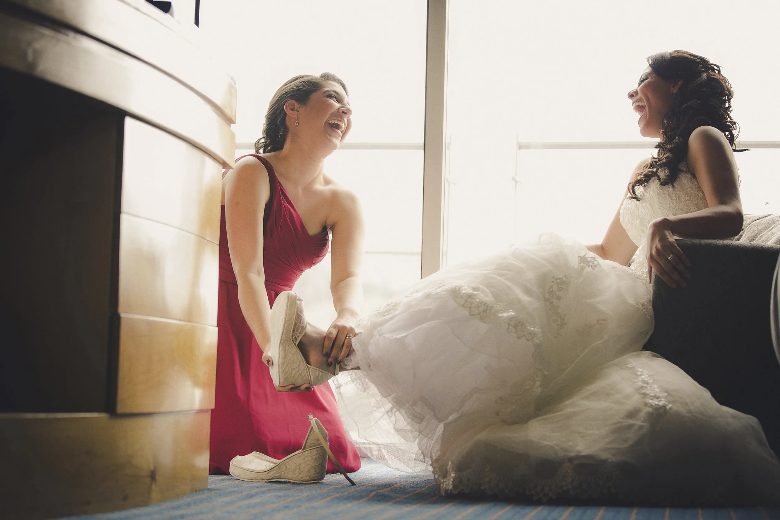 Fotografía documental de mujer ayudando a novia con el vestido, momento previo a la ceremonia.