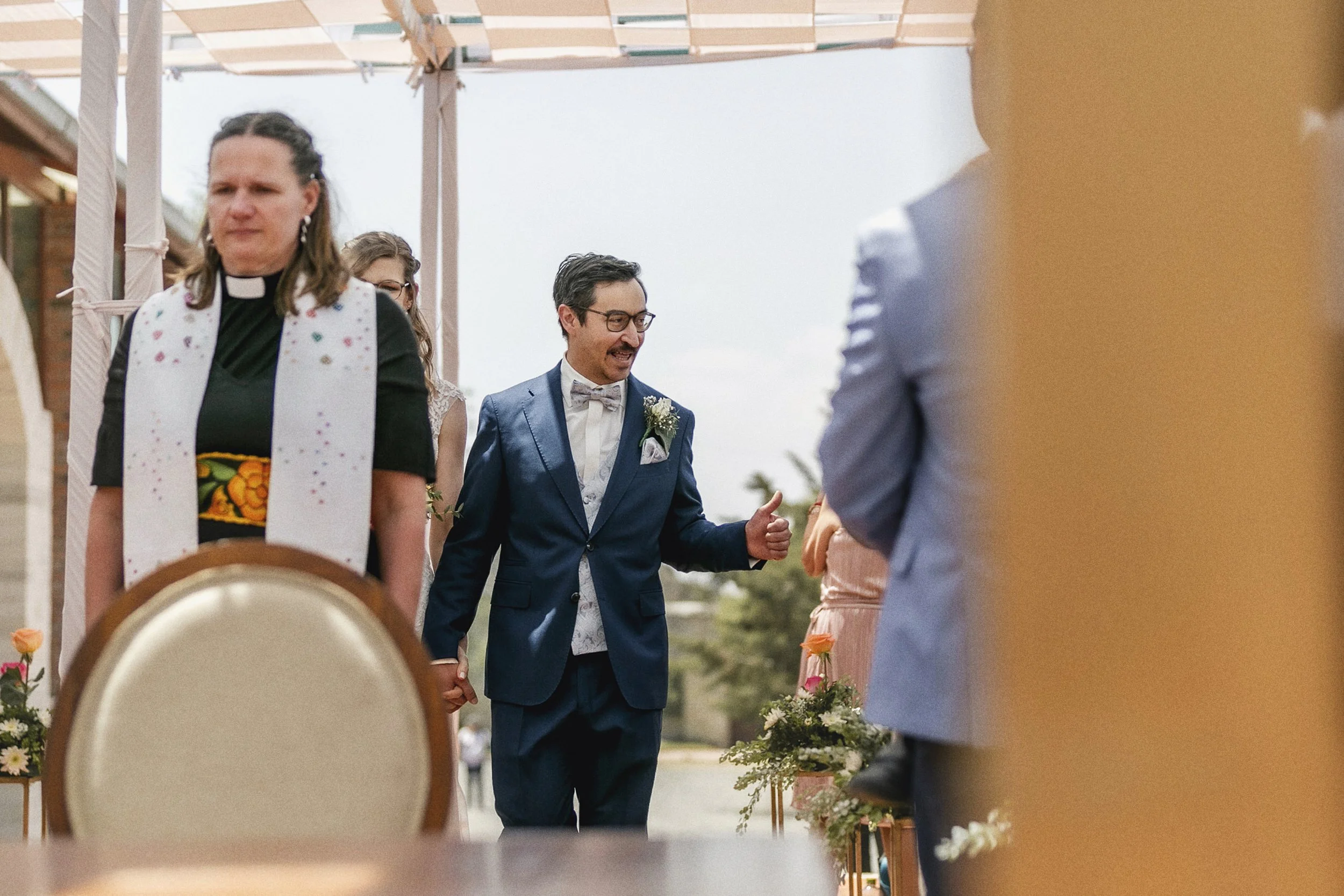Fotografía documental de novio entrando a la celebración acompañado por invitados.