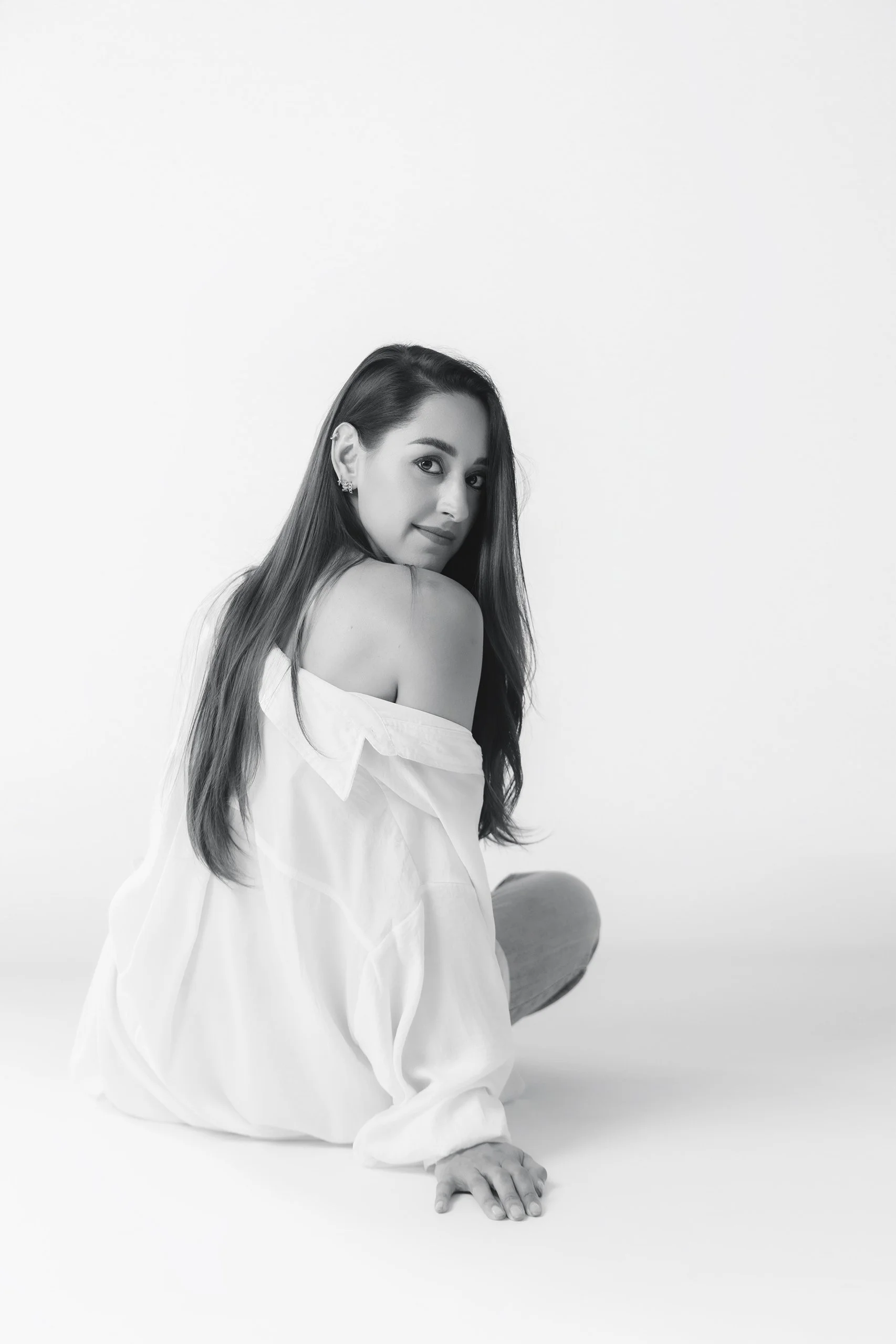 Retrato en blanco y negro de mujer sentada, espalda descubierta y mirada suave hacia cámara