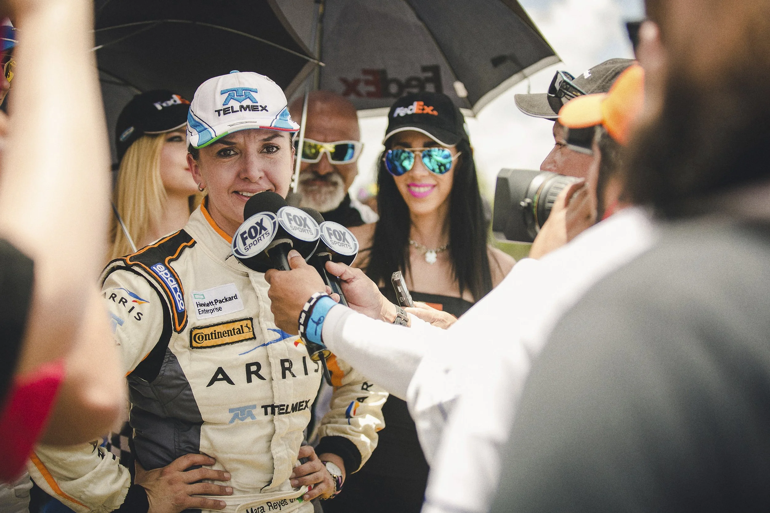 Fotografía documental de mujer piloto siendo entrevistada por medios, escena espontánea y contexto público.