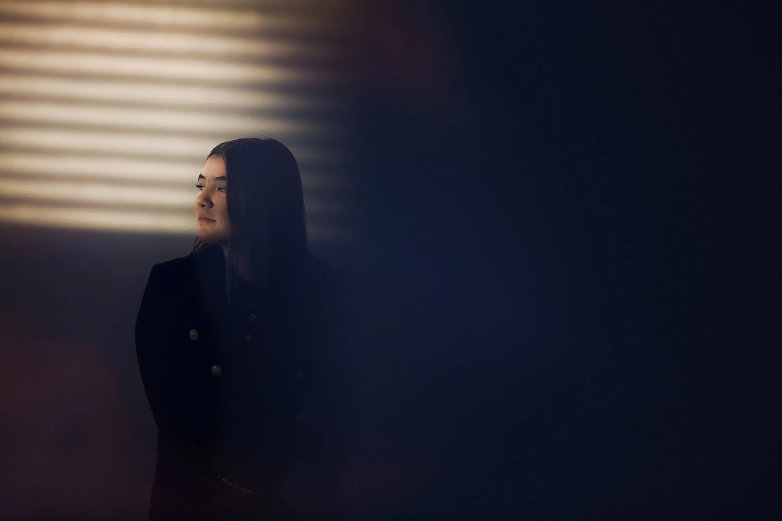 Retrato de mujer en interior con luz lateral suave, rostro parcialmente en sombra.