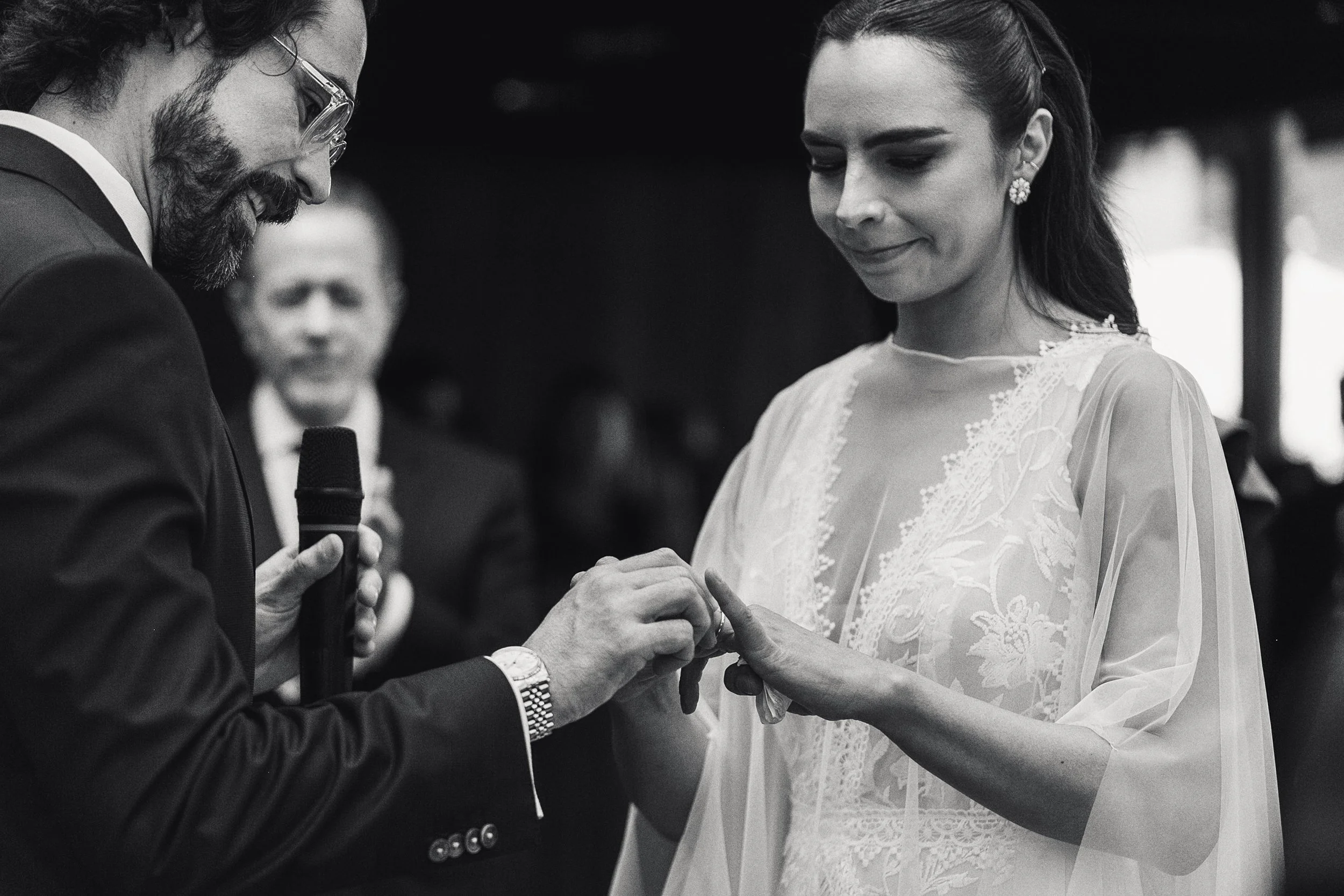 Fotografía en blanco y negro de intercambio de anillos durante ceremonia, manos en primer plano.