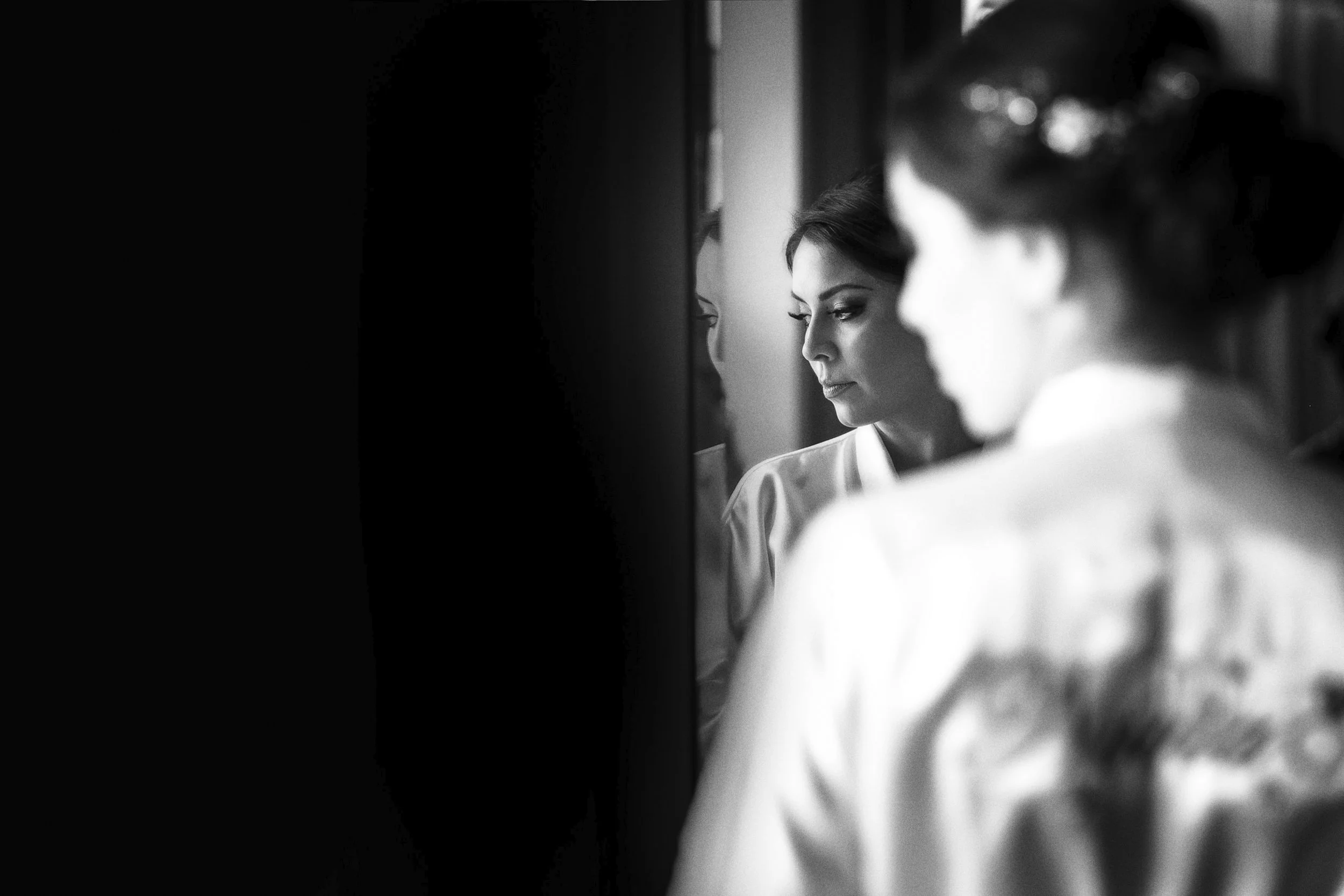 Fotografía en blanco y negro de novia frente al espejo, momento íntimo previo a la ceremonia.