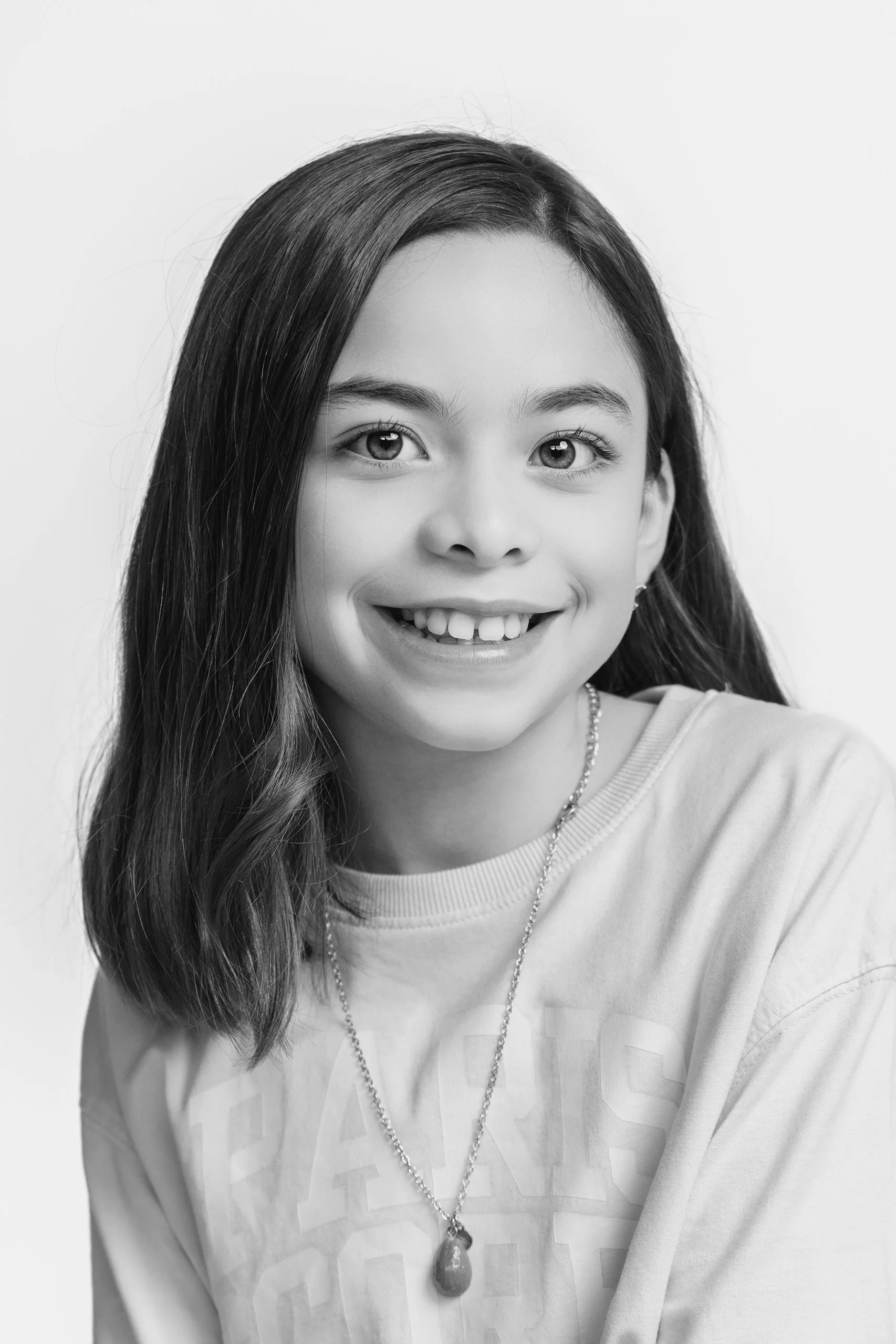Retrato en blanco y negro de niña en primer plano, sonrisa natural y fondo neutro.