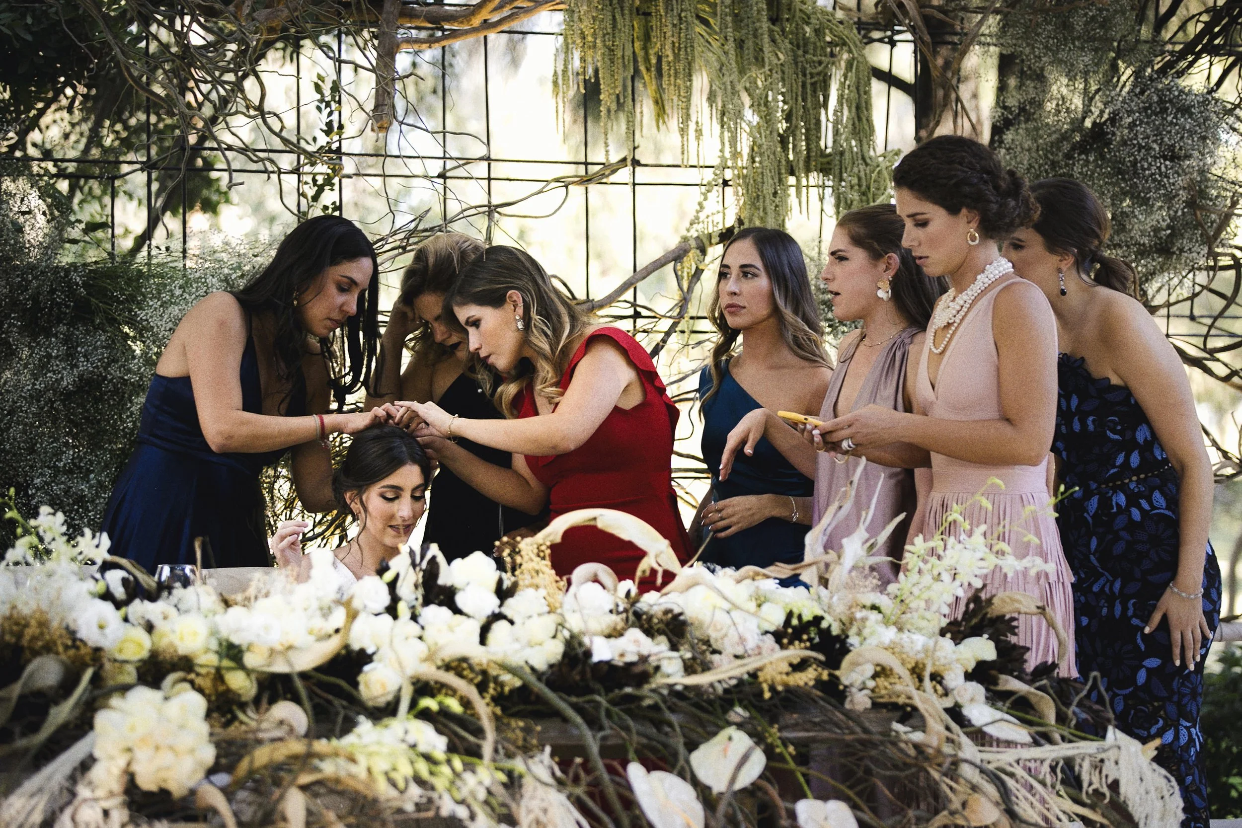 Fotografía documental de mujeres acomodando flores y tocado de la novia durante la preparación.