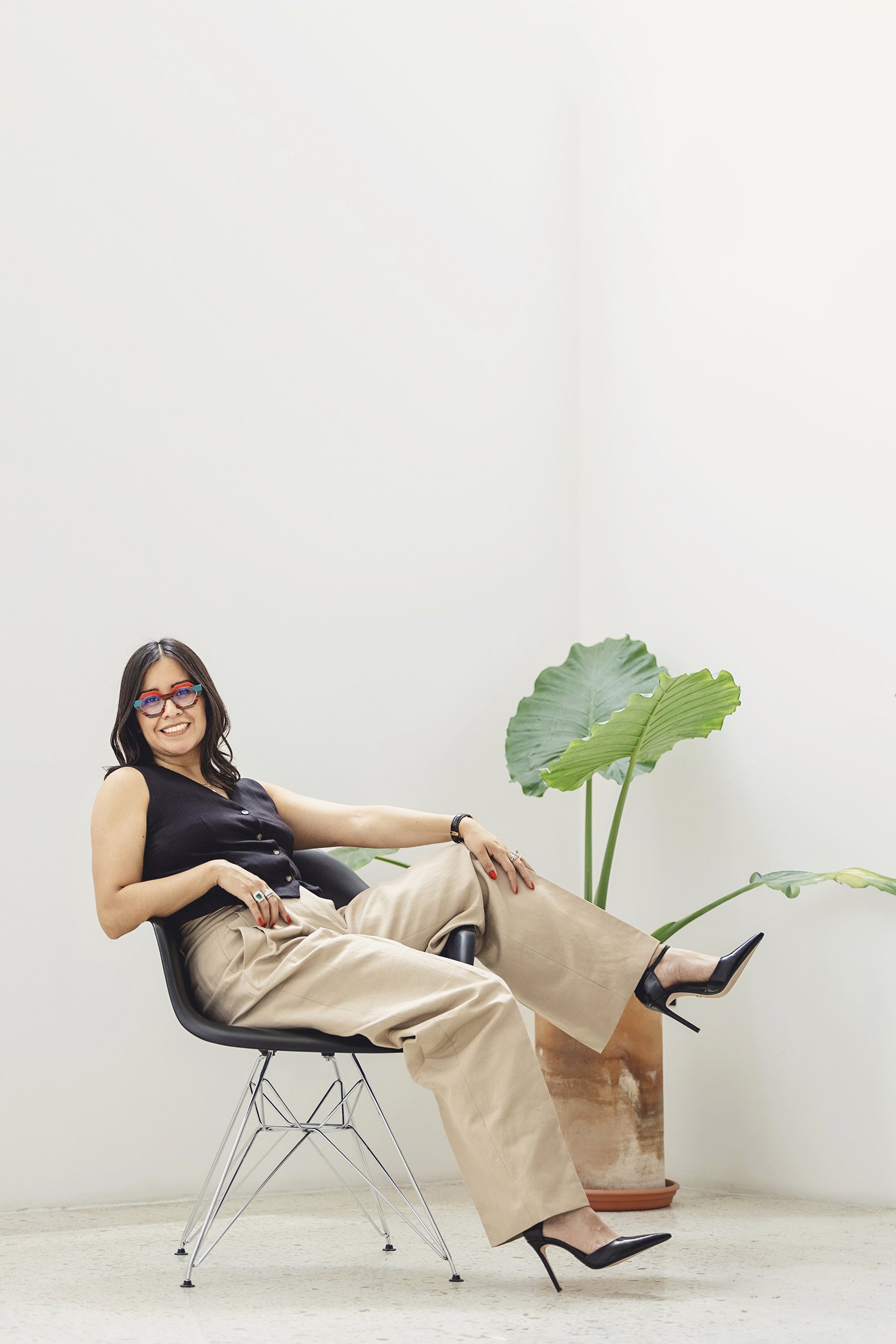 Retrato de mujer sentada en estudio, vestimenta clara, postura relajada y expresión segura.
