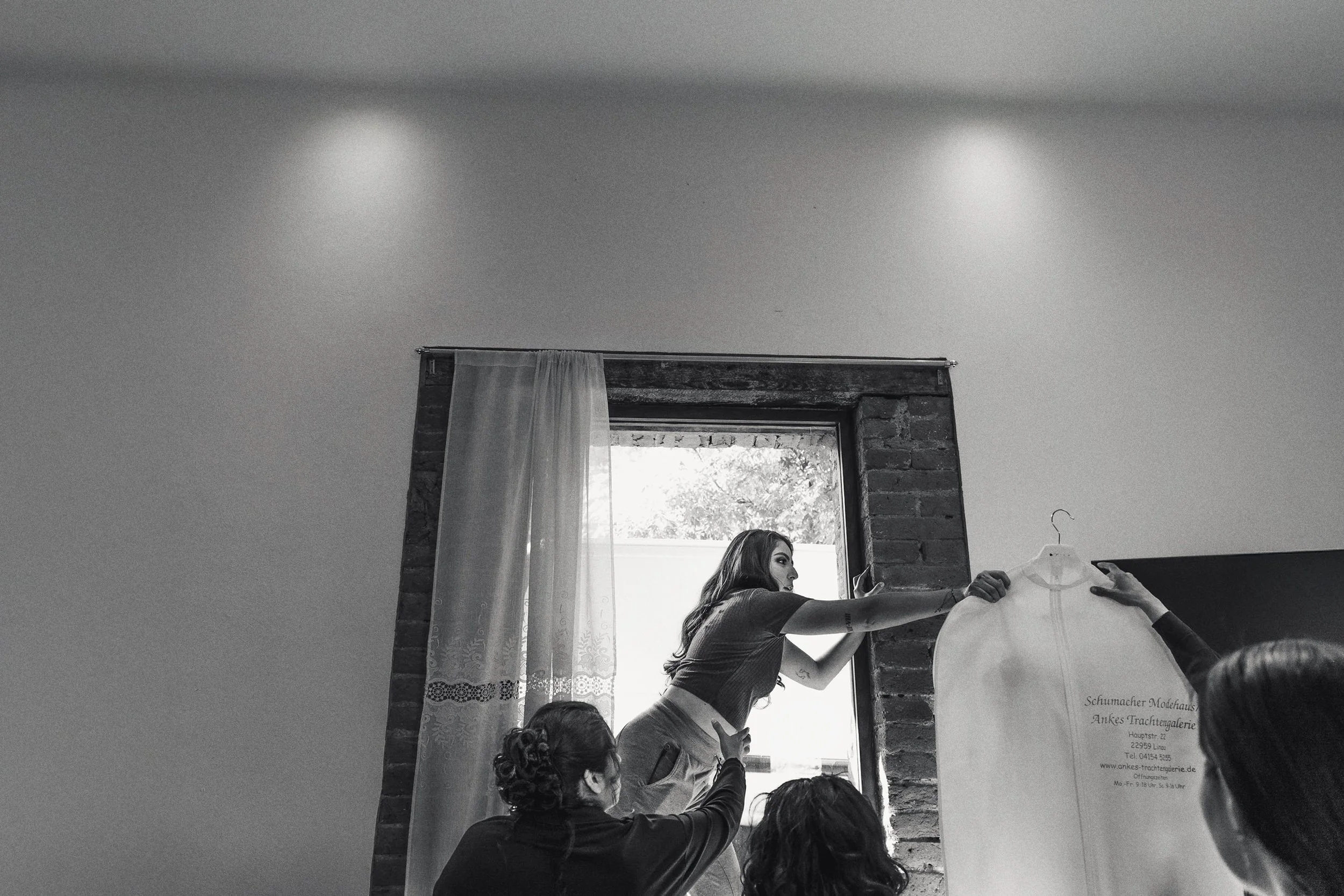 Fotografía documental en blanco y negro de novia lanzando ramo en interior, movimiento y energía del momento.