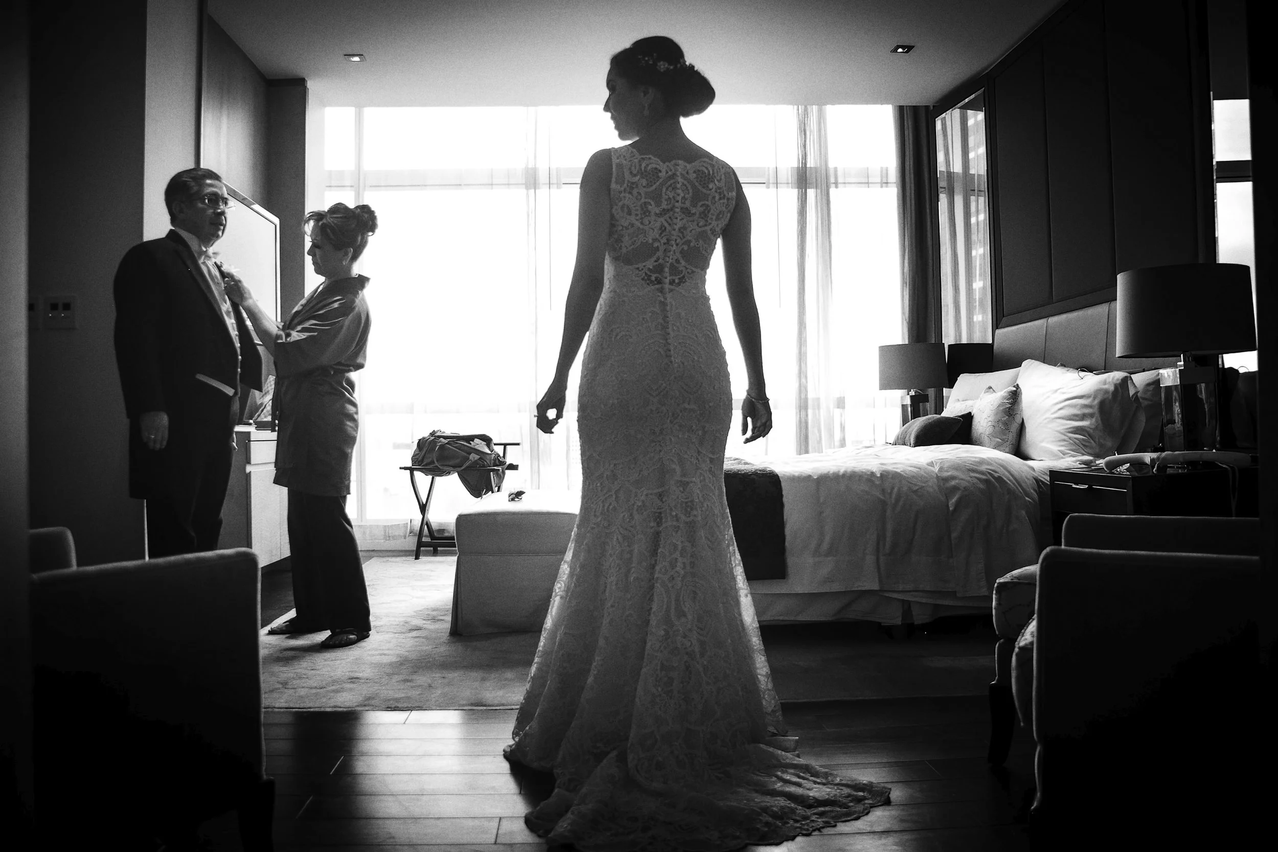 Fotografía en blanco y negro de novia caminando en interior hacia la luz, silueta y profundidad.