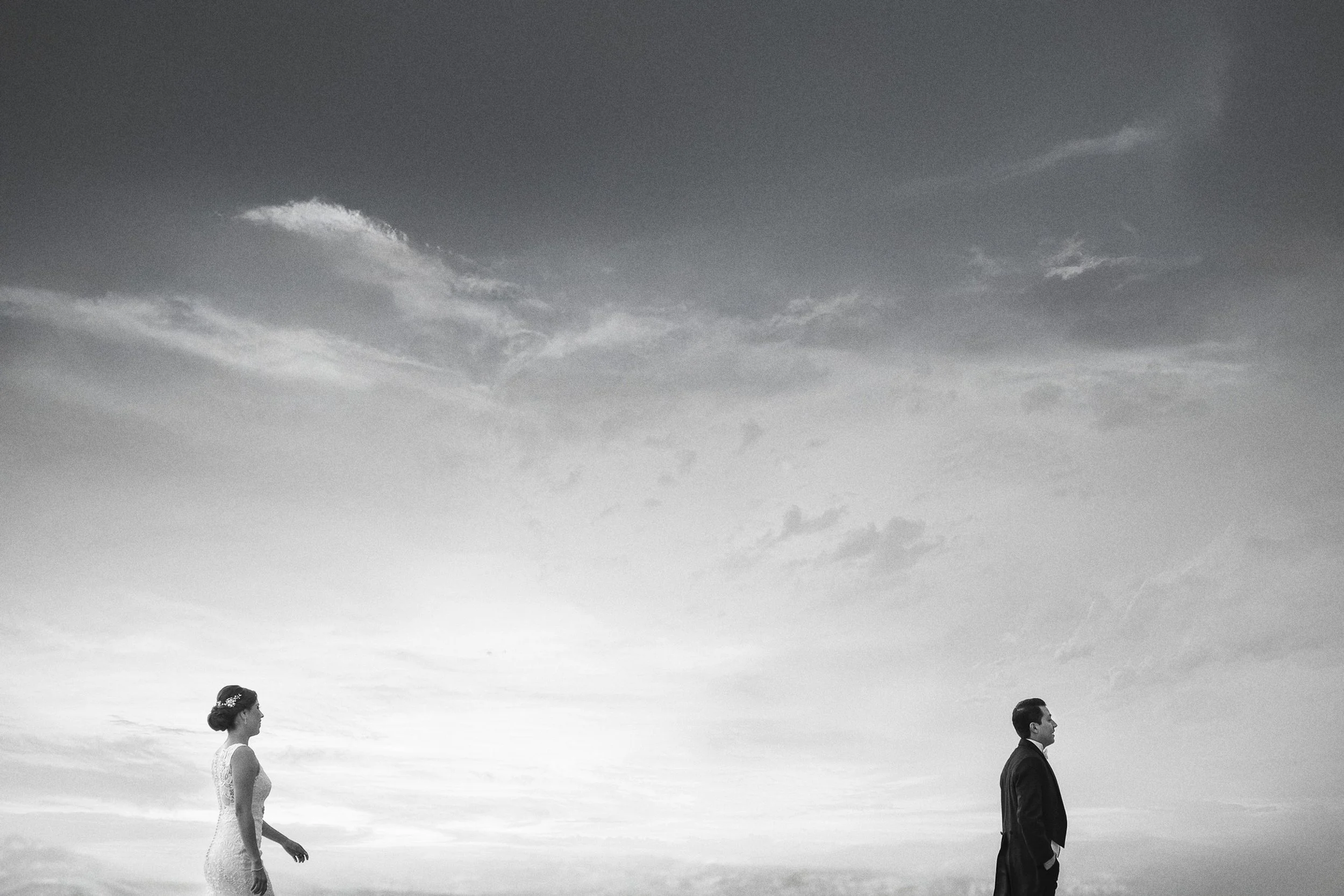 Fotografía en blanco y negro de pareja separada por distancia, figuras pequeñas frente al paisaje.