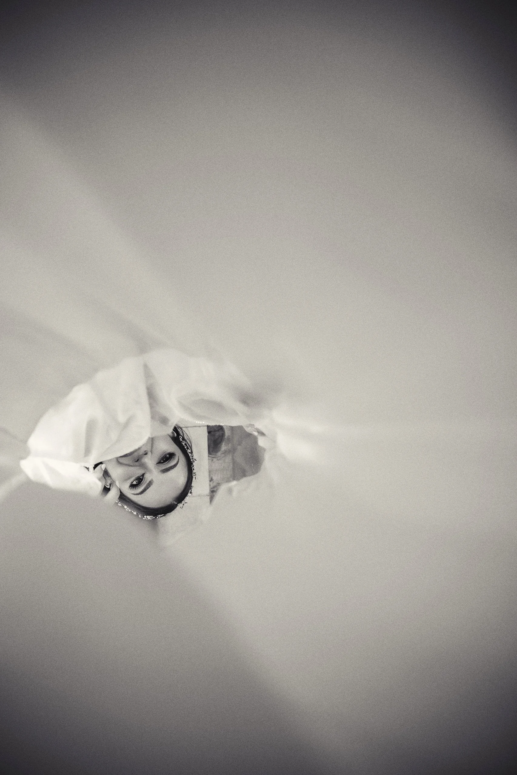 Fotografía en blanco y negro de novia reflejada en espejo, encuadre invertido y gesto sereno.