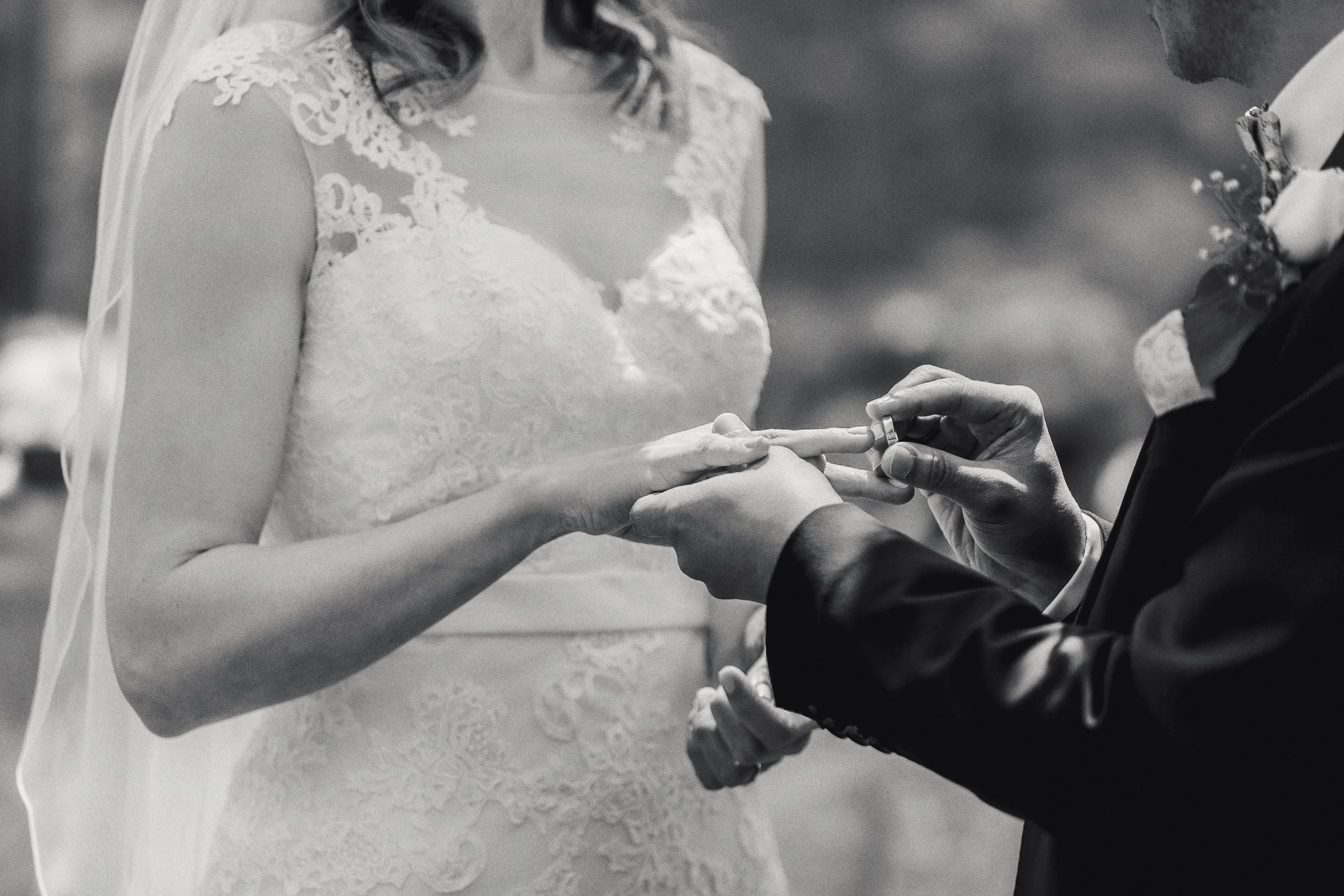 Fotografía en blanco y negro de intercambio de anillos durante la ceremonia, manos en primer plano.