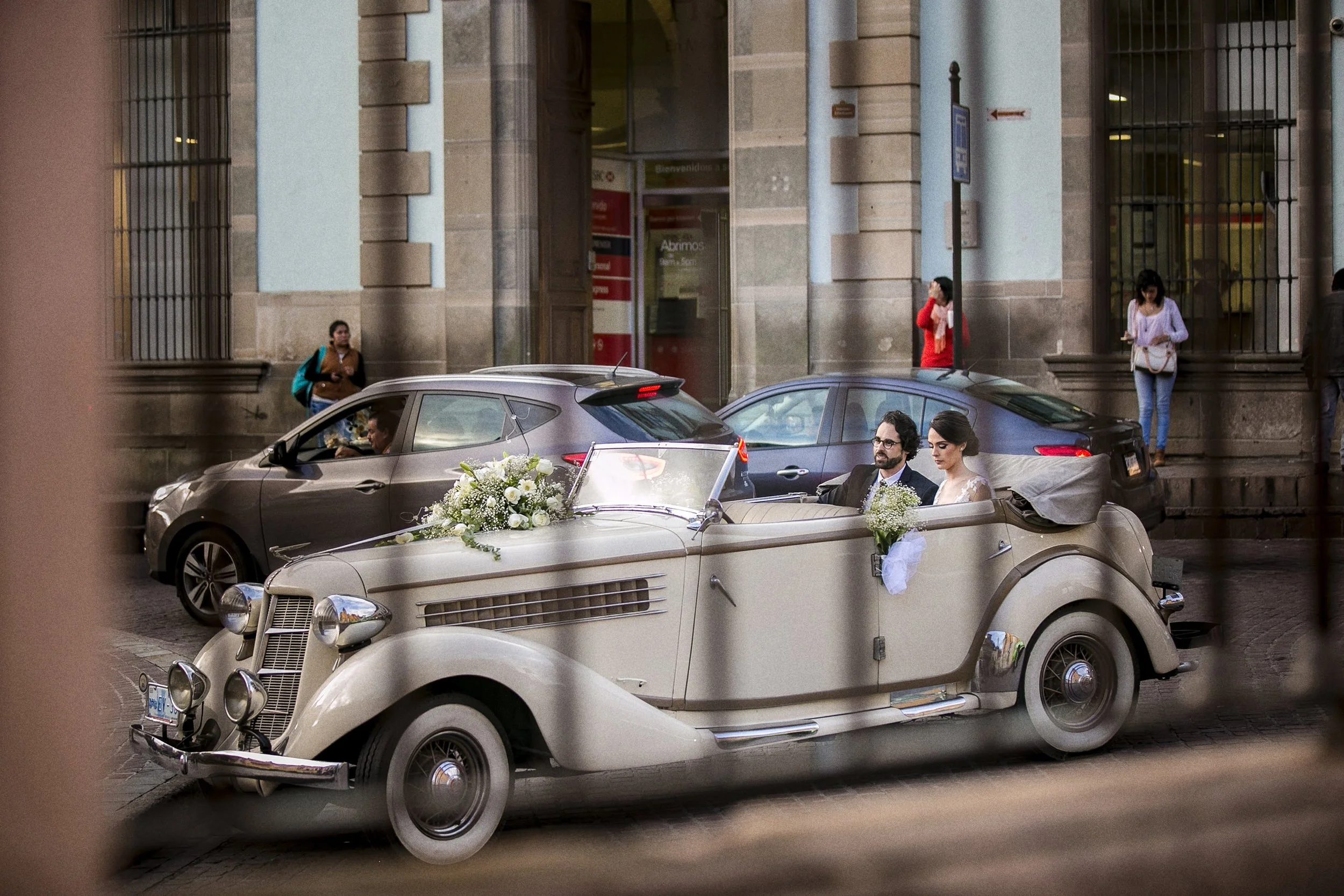Fotografía documental de automóvil decorado saliendo del lugar de la ceremonia.