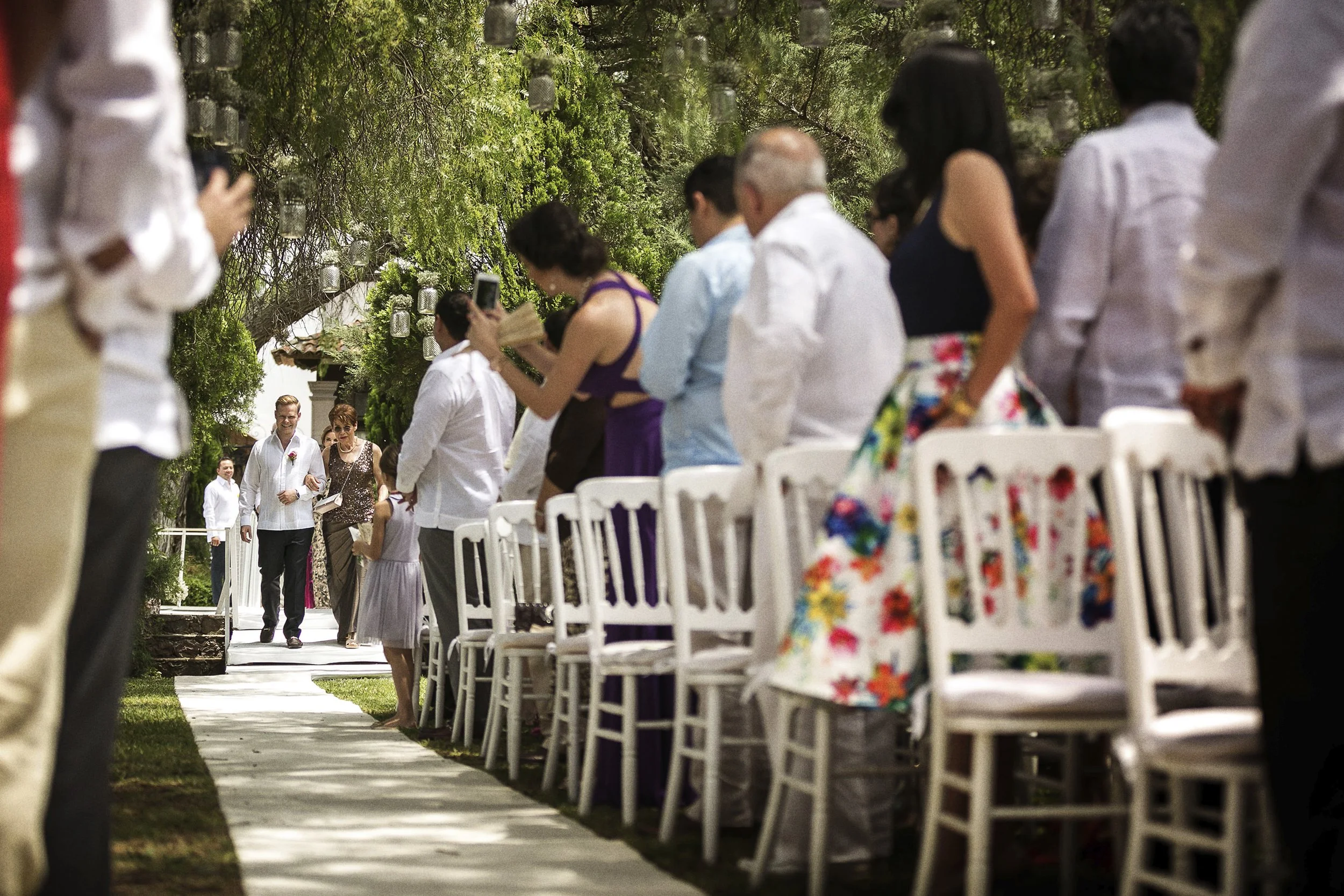 Fotografía documental de invitados sentados en fila durante ceremonia al aire libre.