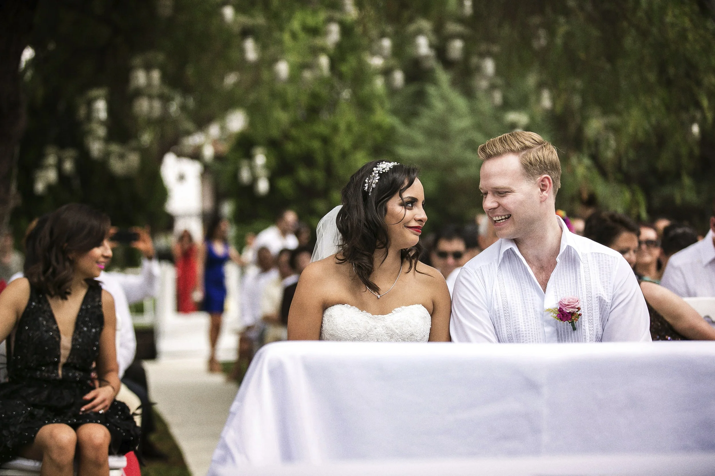 Fotografía documental de novios sentados juntos durante ceremonia civil, miradas cruzadas.