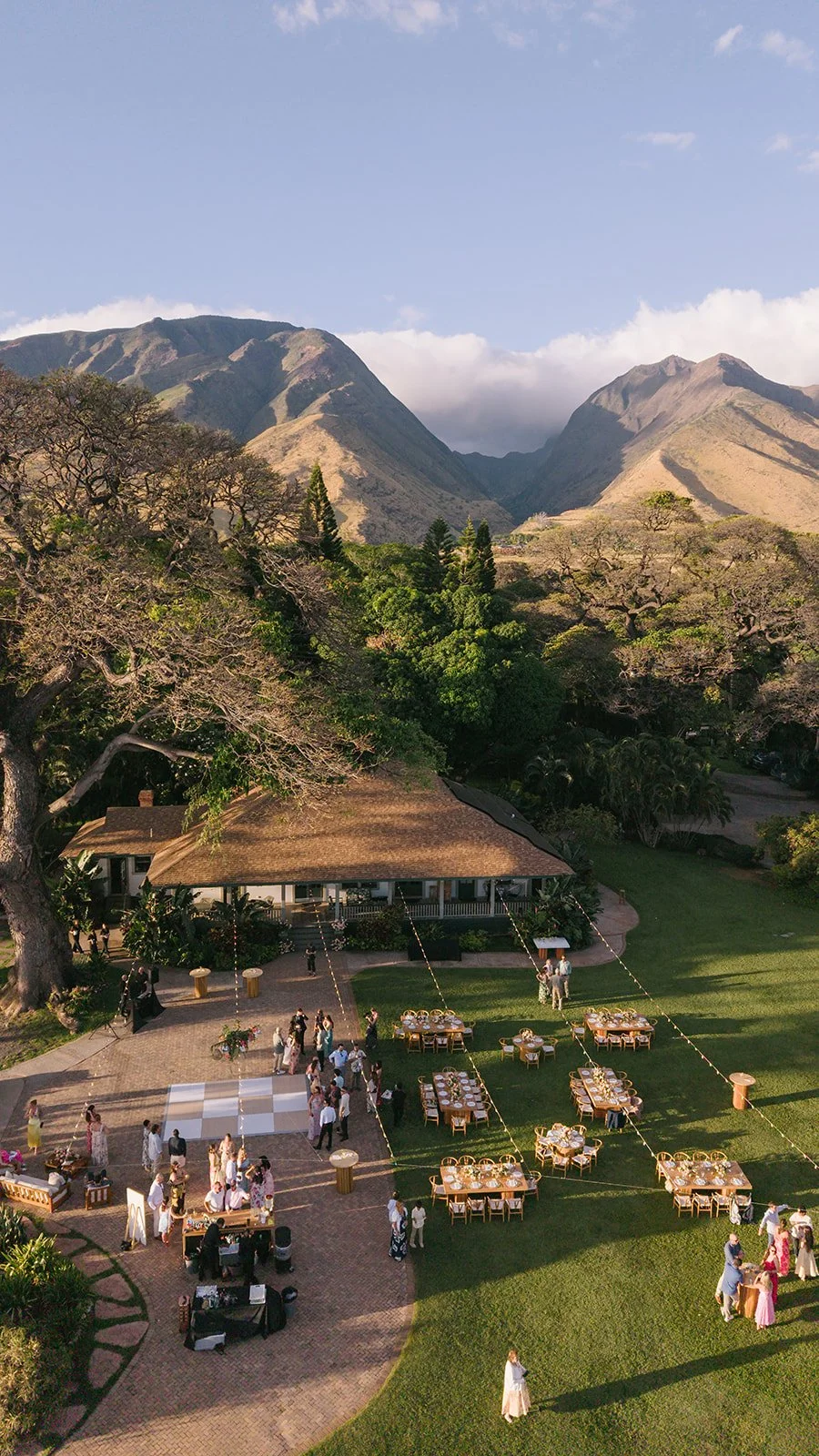 Aerial view of an outdoor wedding reception at [venue name] on Maui with long tables, string lights and a dance floor