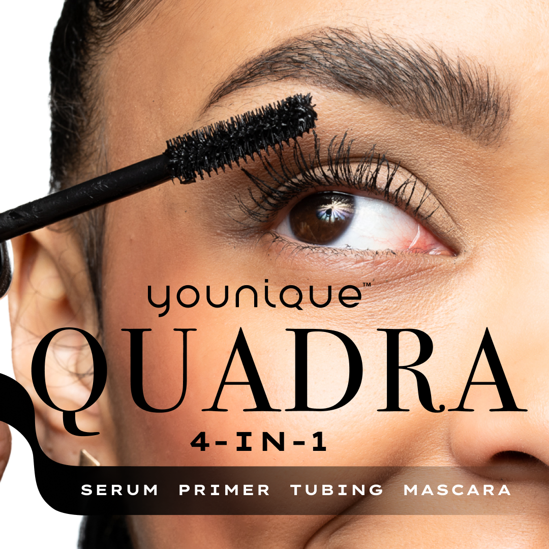 Close-up of a woman with brown eyes applying black mascara to her upper eyelashes with a mascara wand. The image features product branding text, including 'Younique Quadra 4-in-1 Serum Primer Tubing Mascara'