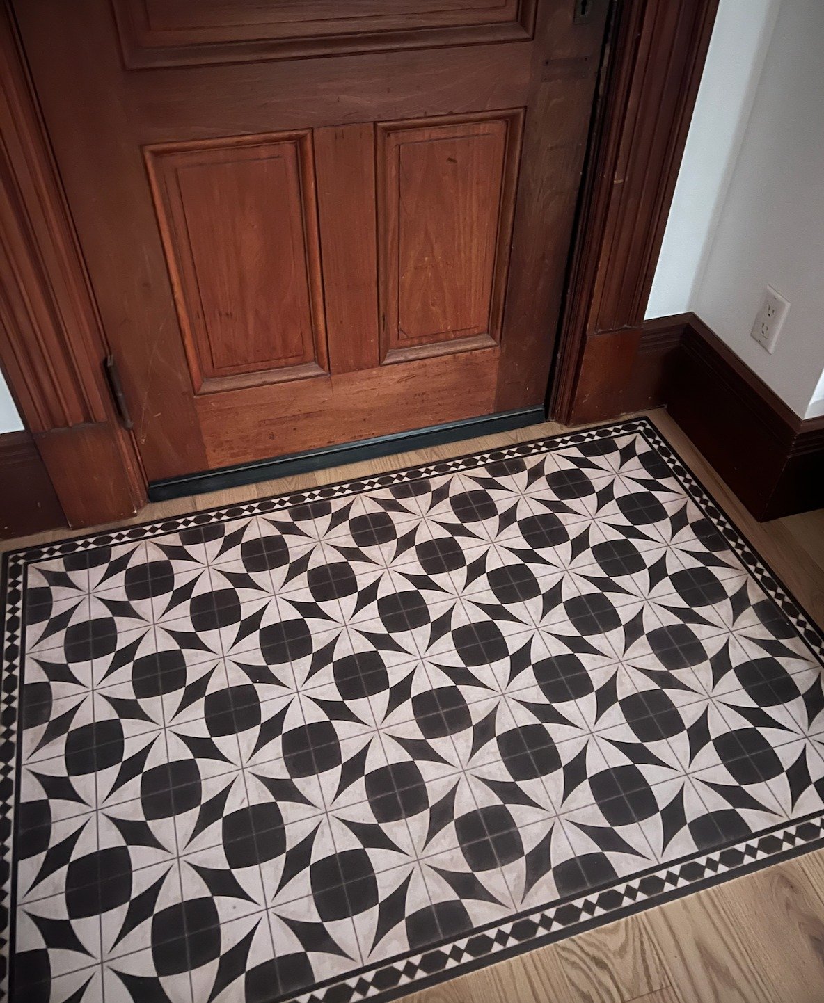 Are you entryway deficient? Have a low hanging door? 
I used this vintage inspired vinyl floorcloth to provide a faux foyer that makes us stop and remove our shoes. It is thin enough that the door swings right over it. The tile pattern reminds me of 