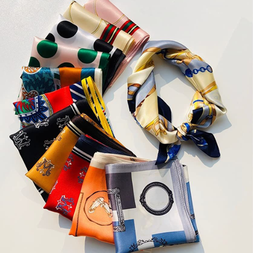 Arranged colorful silk scarves with various patterns and prints, including polka dots, floral, geometric, and abstract designs.