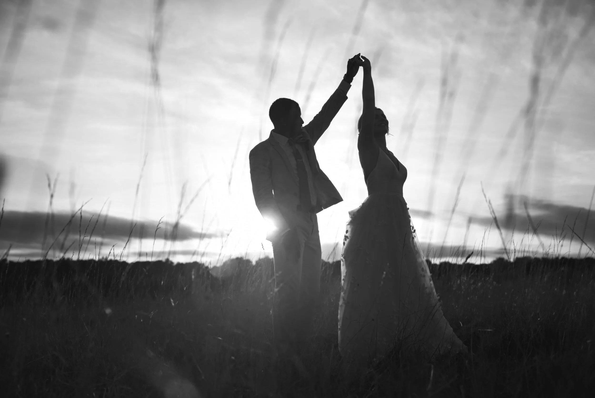 Silhouette of a couple dancing in a field at sunset