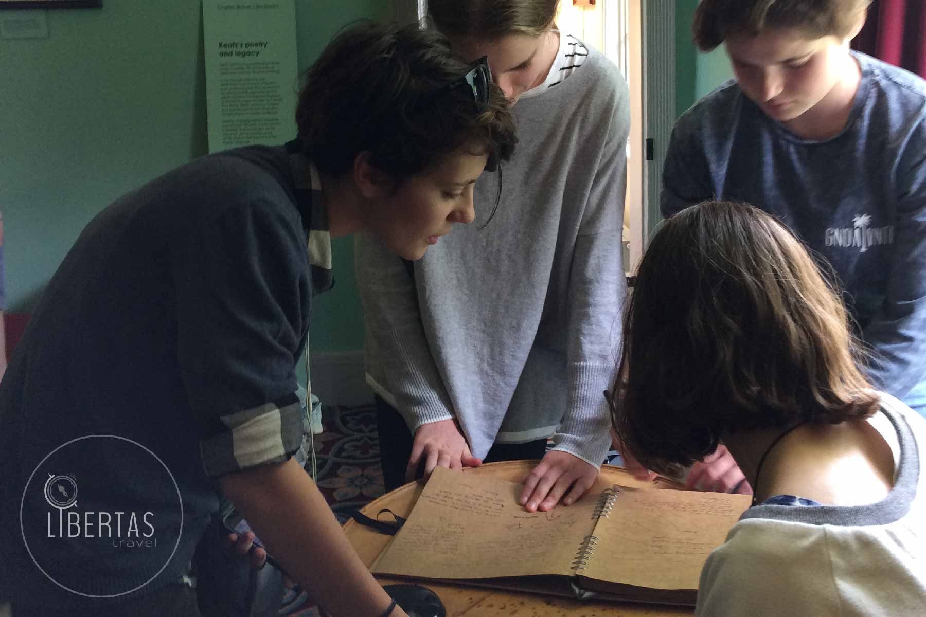 Students gathered around reading from a book inside Keats House