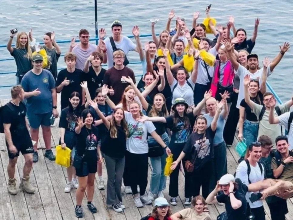 A large group of Australian high school students cheering on a waterfront pier during a Libertas Travel excursion — bespoke itineraries for whole year groups and subject-focused student groups.