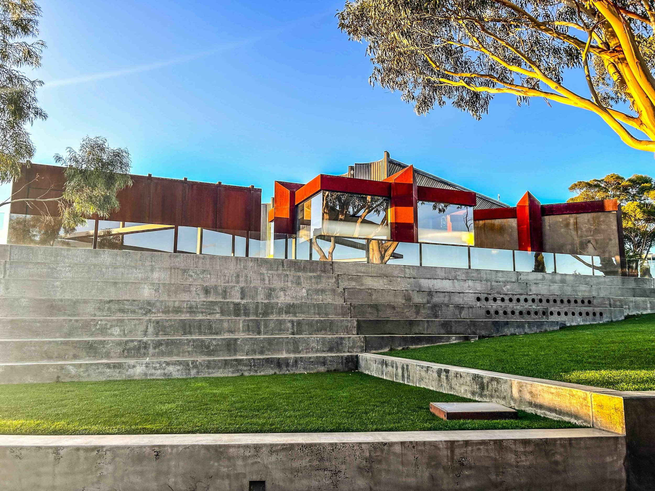 The striking Brutalist exterior of MONA – Museum of Old and New Art in Hobart, Tasmania, featuring rusted Corten steel panels, glass facades and terraced concrete steps