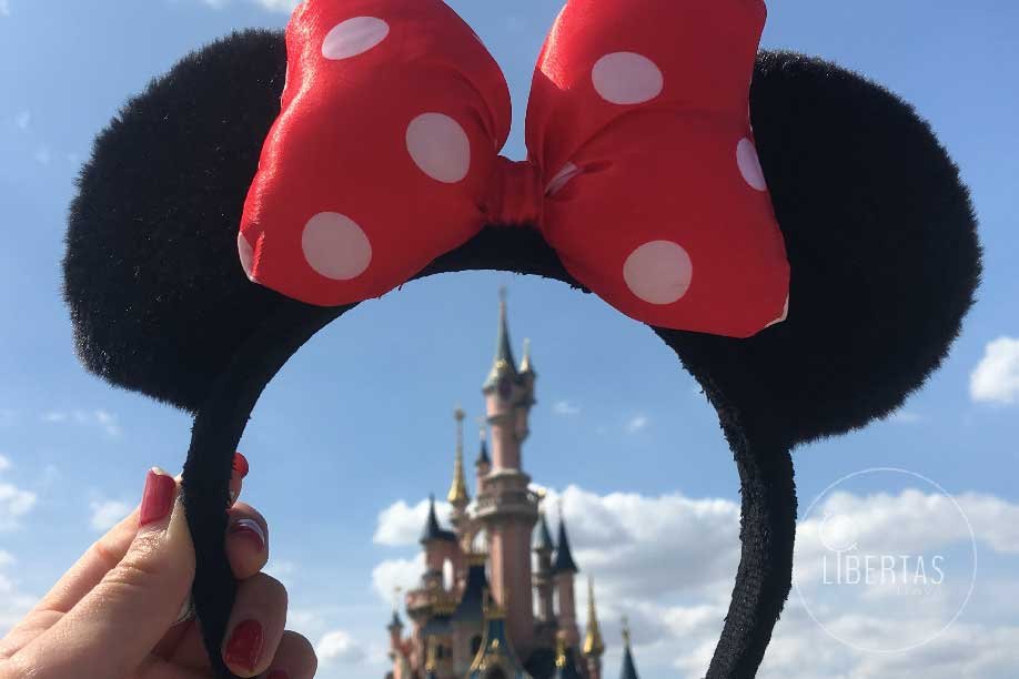 A day at Disneyland having fun holding a Minnie mouse head band up to frame the iconic Disney land theme park