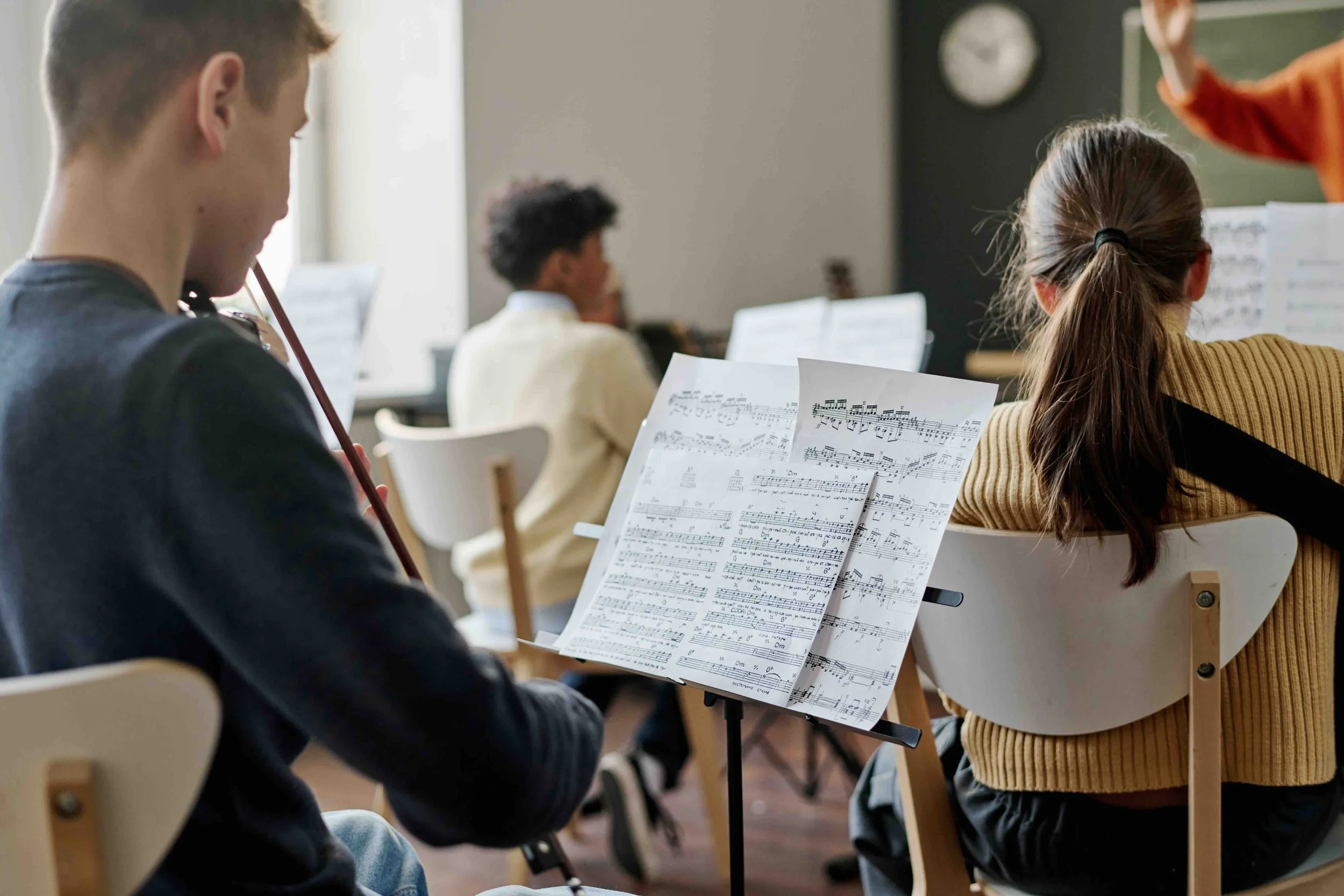 High school students reading sheet music and rehearsing in an orchestra ensemble — reflecting the performance and musical depth of Libertas Travel's Creative Arts and CAPA school excursions.