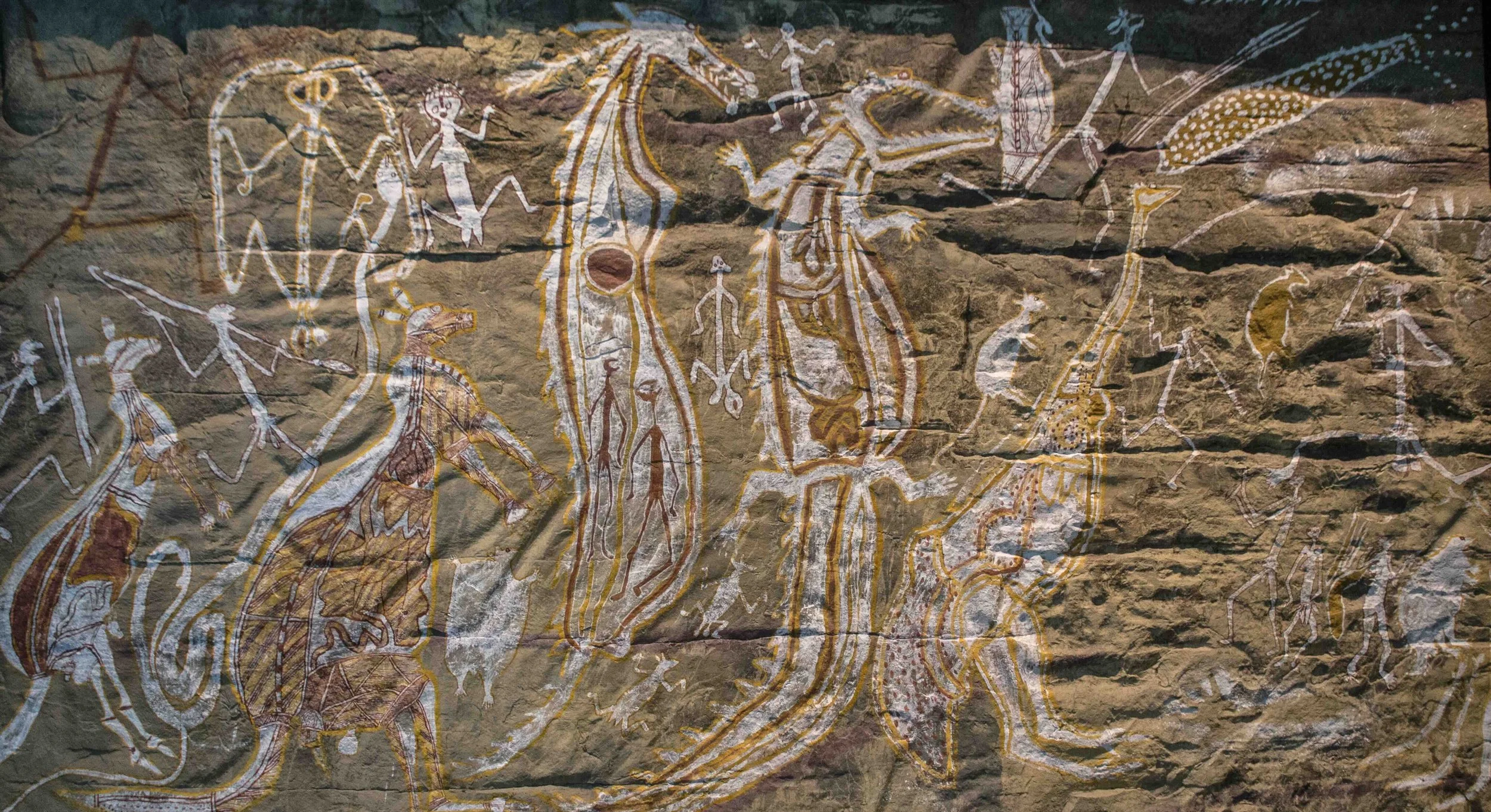 Ancient First Nations rock art depicting Dreamtime figures, animals and ancestral beings — connecting Australian high school students to Country and Indigenous culture on a Libertas Travel excursion.