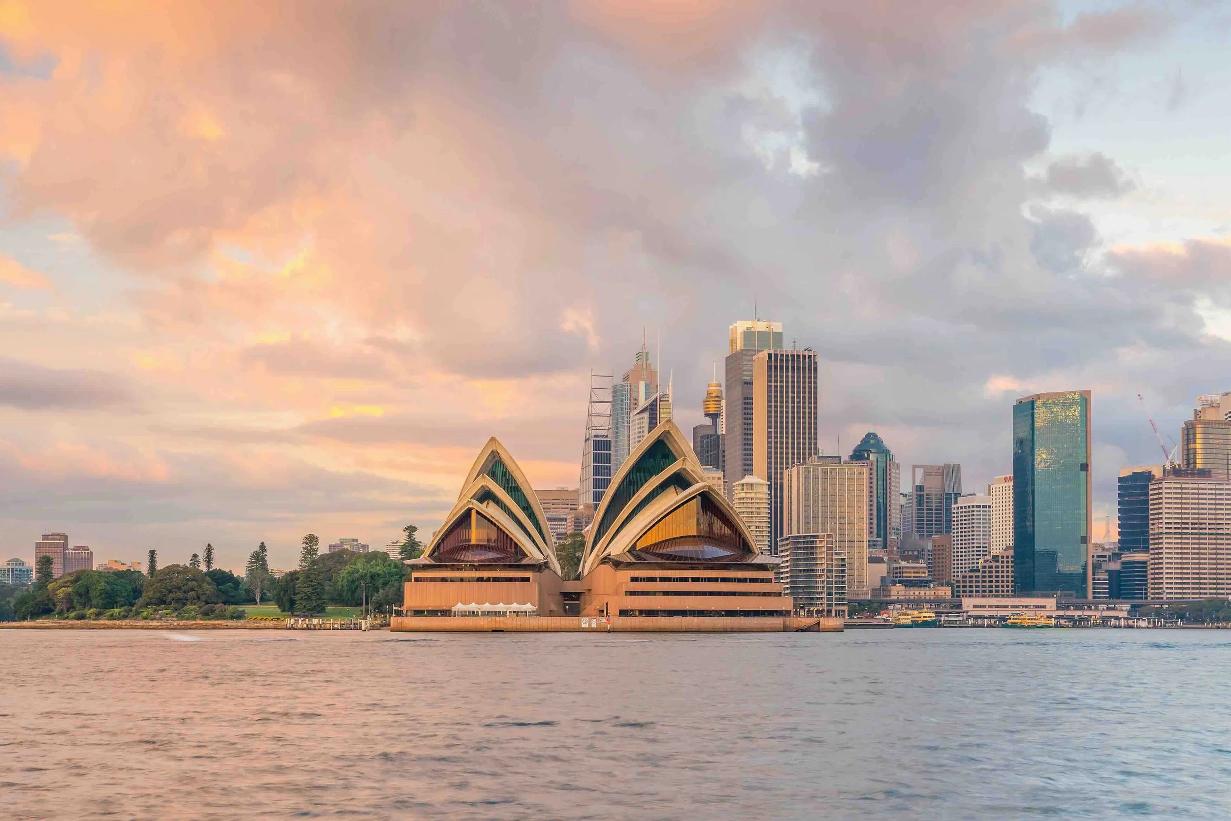 The Sydney Opera House glowing at sunset over a pastel-coloured harbour skyline — the visual arts and architecture centrepiece of Libertas Travel's Sydney Colour high school excursion.