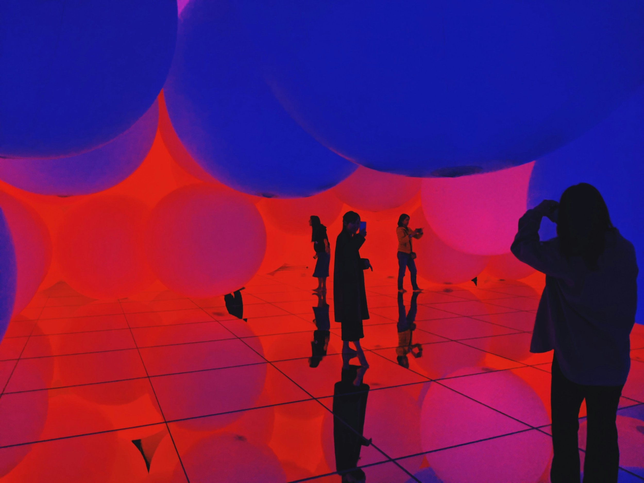 Visitors explore a large-scale interactive digital art installation at TeamLab Planets Tokyo, surrounded by light, color, and water in a futuristic, sensory-rich environment.