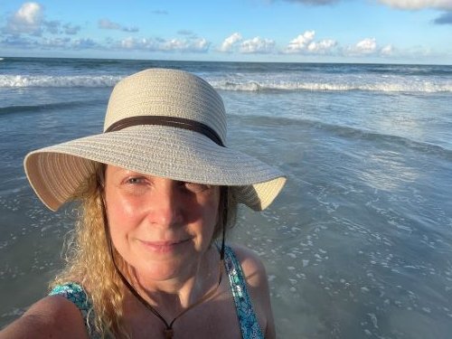 Lori on the beach in a straw hat