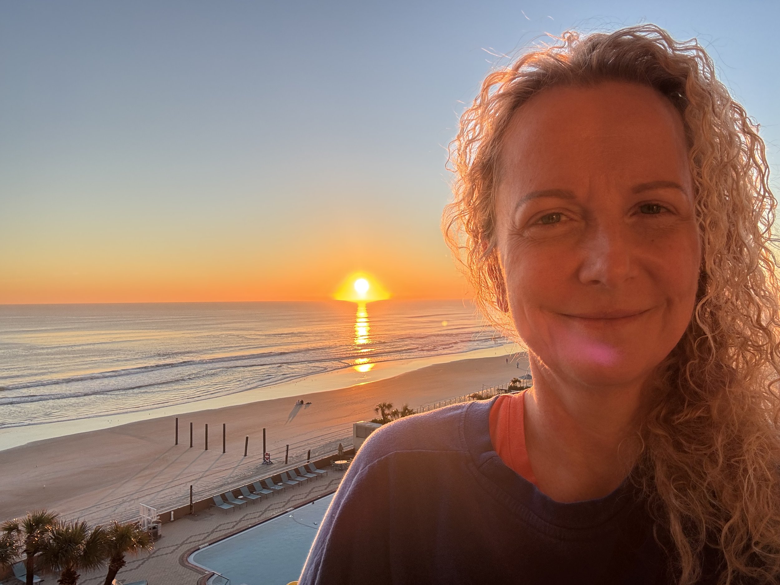 Lori smiling on the beach at sunrise