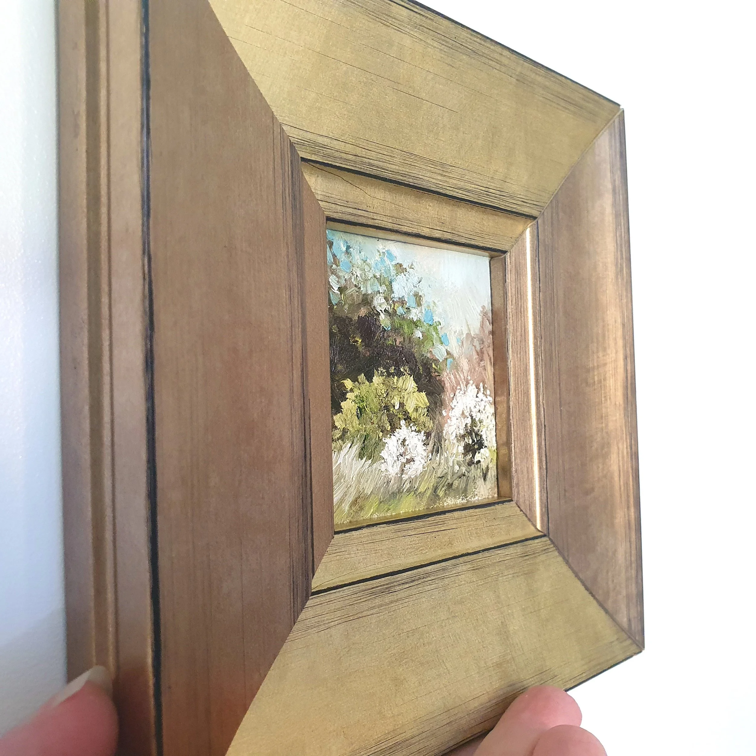 Framed miniature oil painting of rustic country scene with white blossom tree.