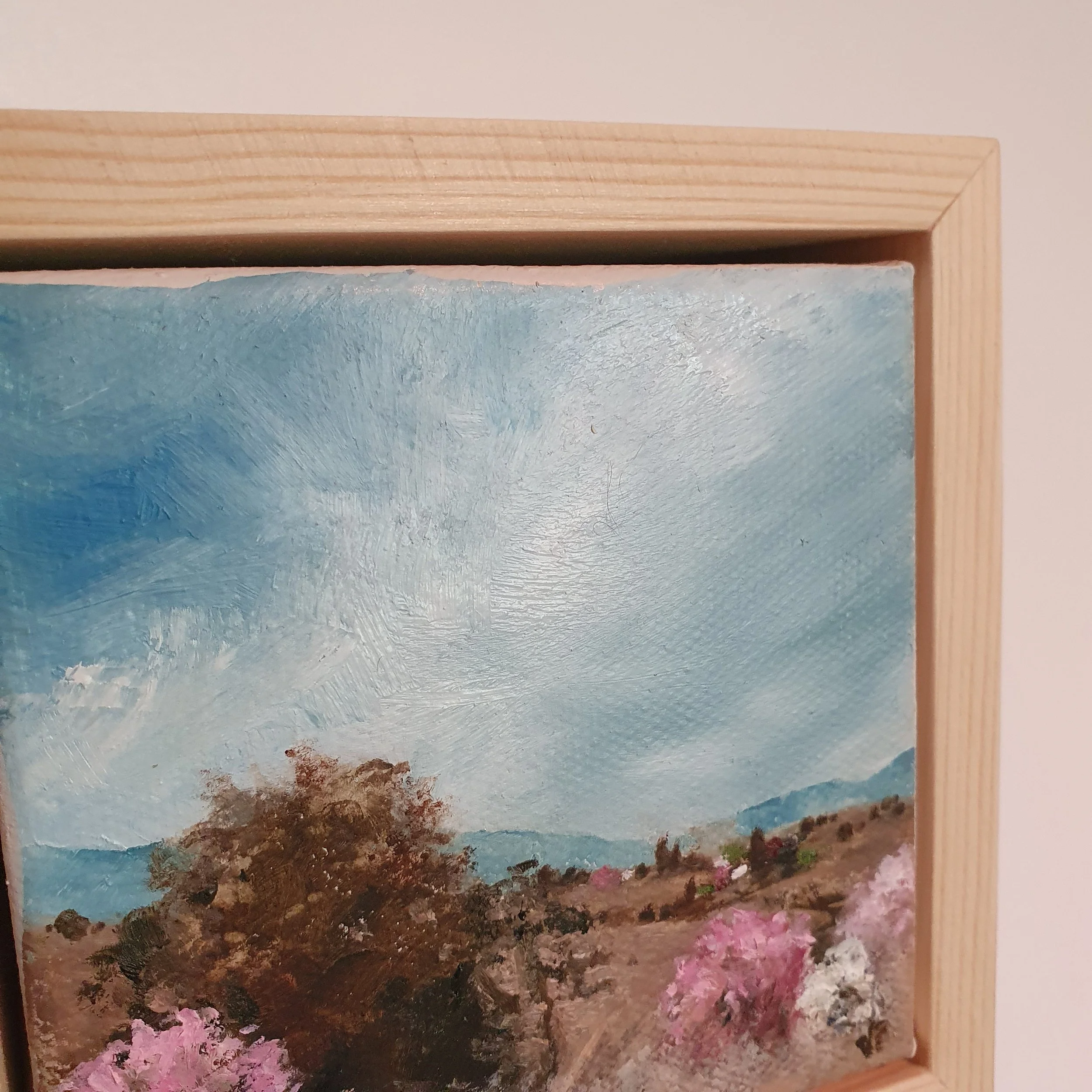 Mini oil painting of country landscape in natural earth tones of light brown and white with pink cherry blossom.