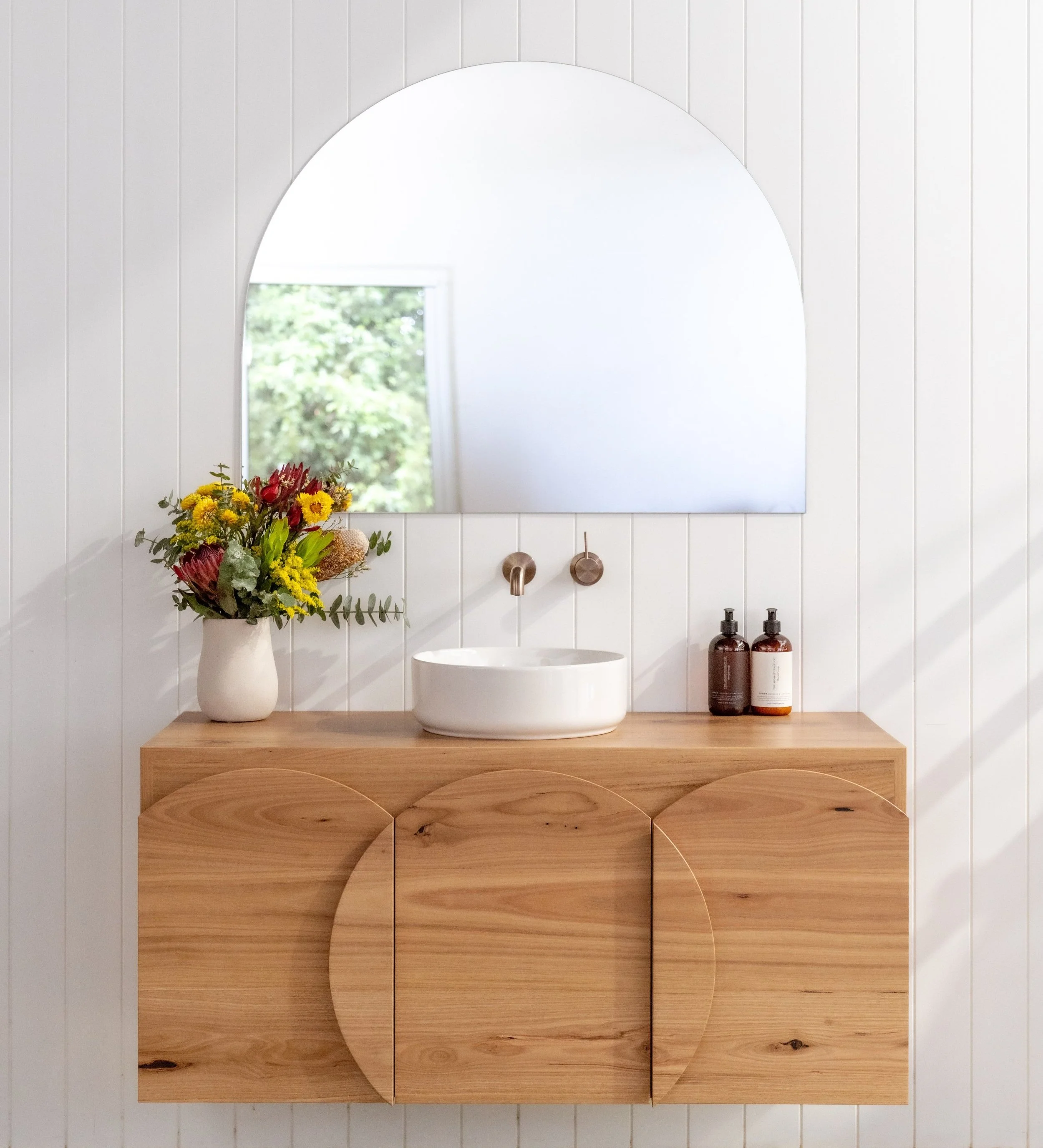 Arcadia: A custom, bespoke Australian native hardwood bathroom vanity in solid Feature-Grade Blackbutt, featuring arched doors and semi-round solid timber handles.