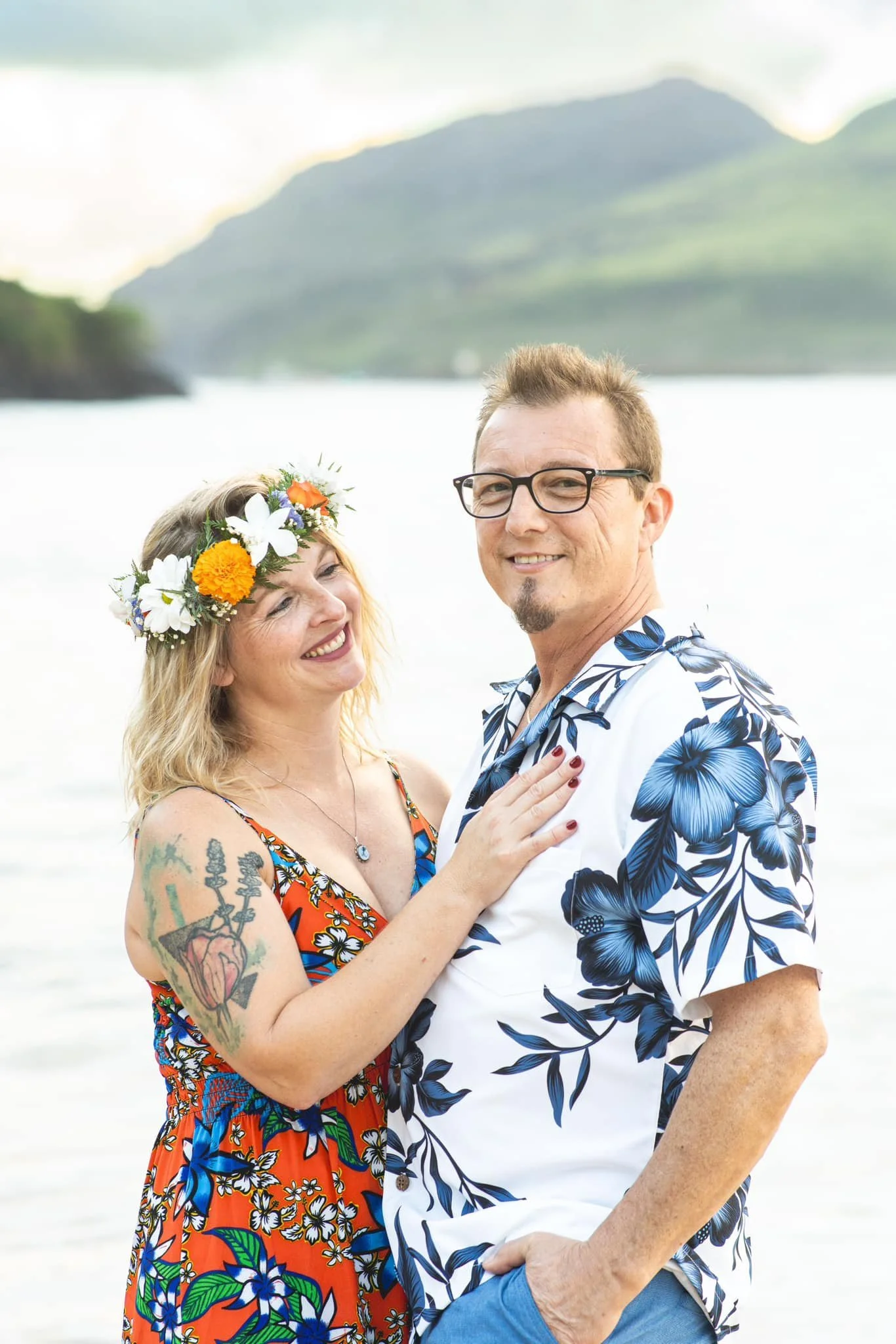 Smiling couple on a Kauai beach, the woman wearing a tropical flower crown.