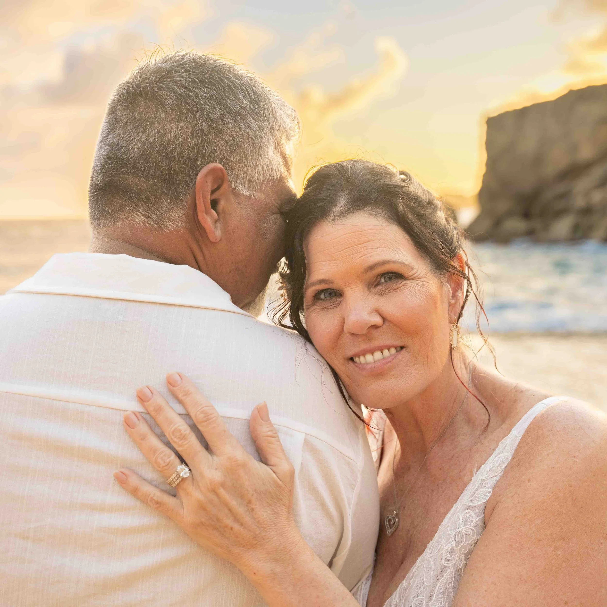 Woman smiling at the camera while hugging her partner at Shipwreck Beach, Kauai.