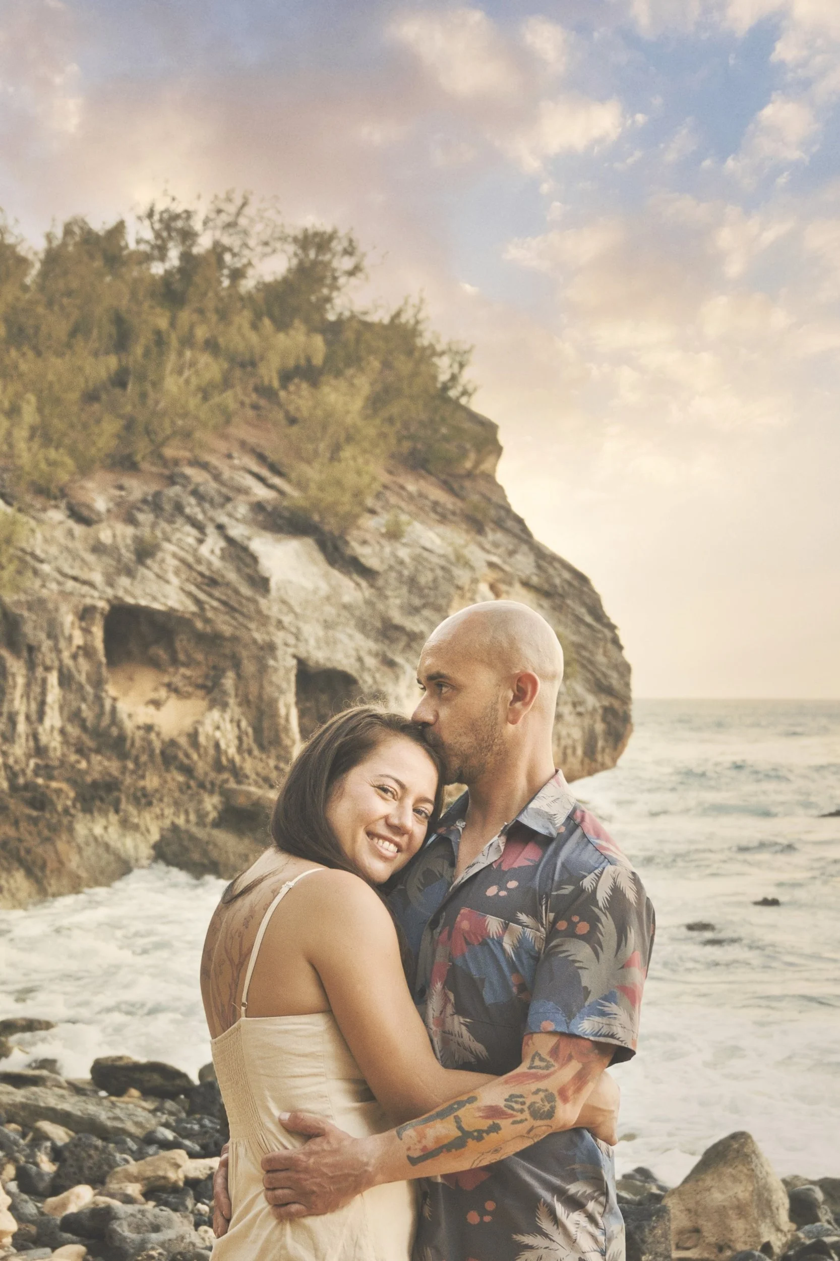 Couple sharing a tender embrace on the rocks at Shipwreck Beach, Kauai.