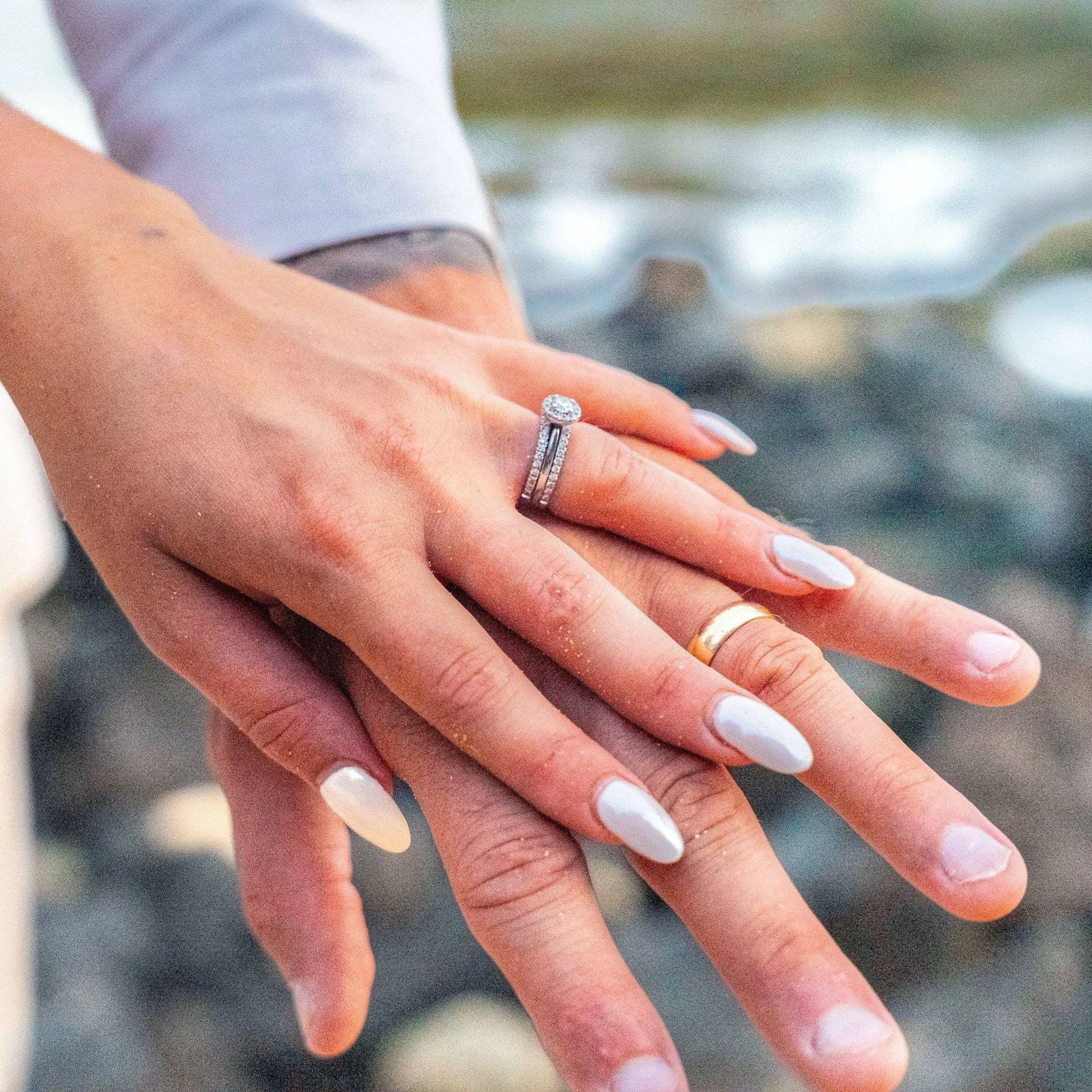 Close-up of a newlywed couple's hands showing their wedding rings on a Kauai beach.
