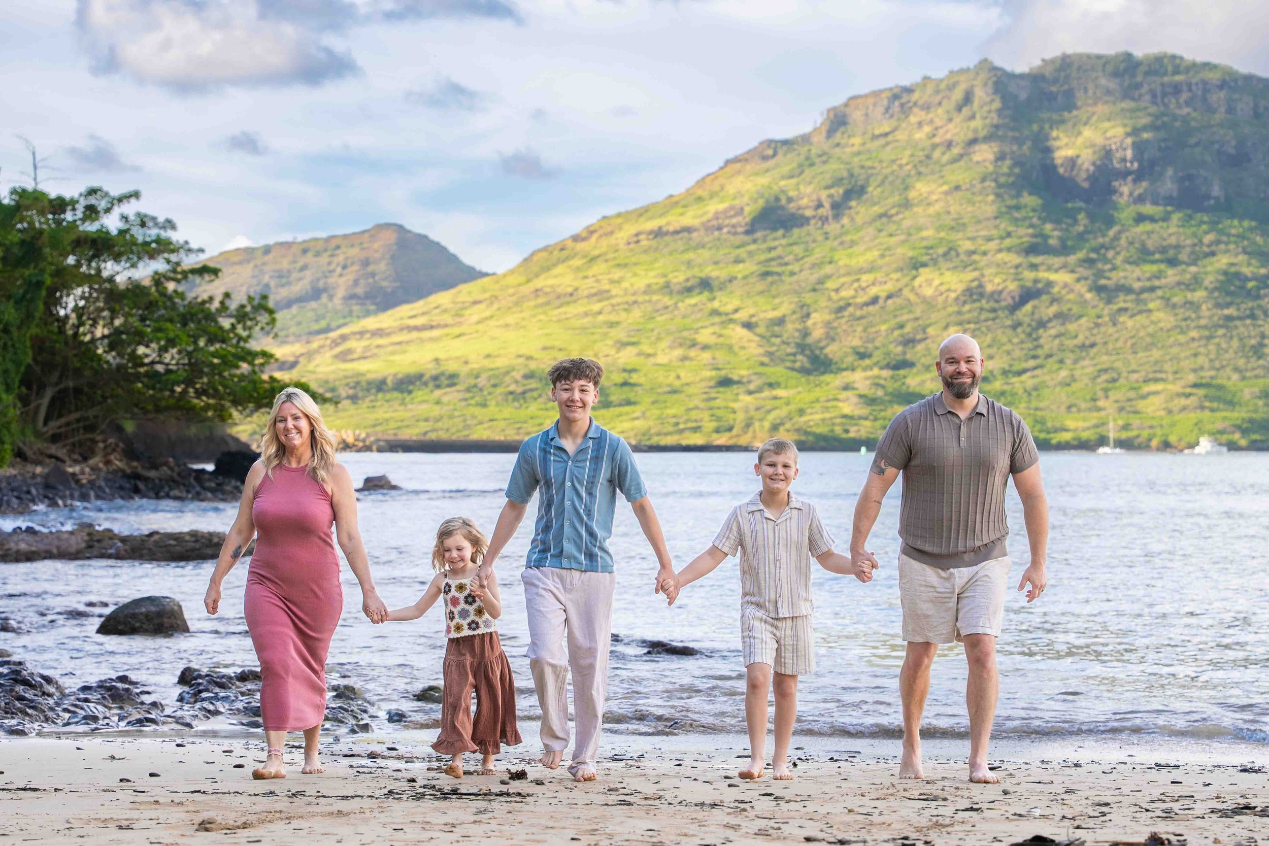 Mom smiling with her three teenagers in a close-up on a Kauai beach.