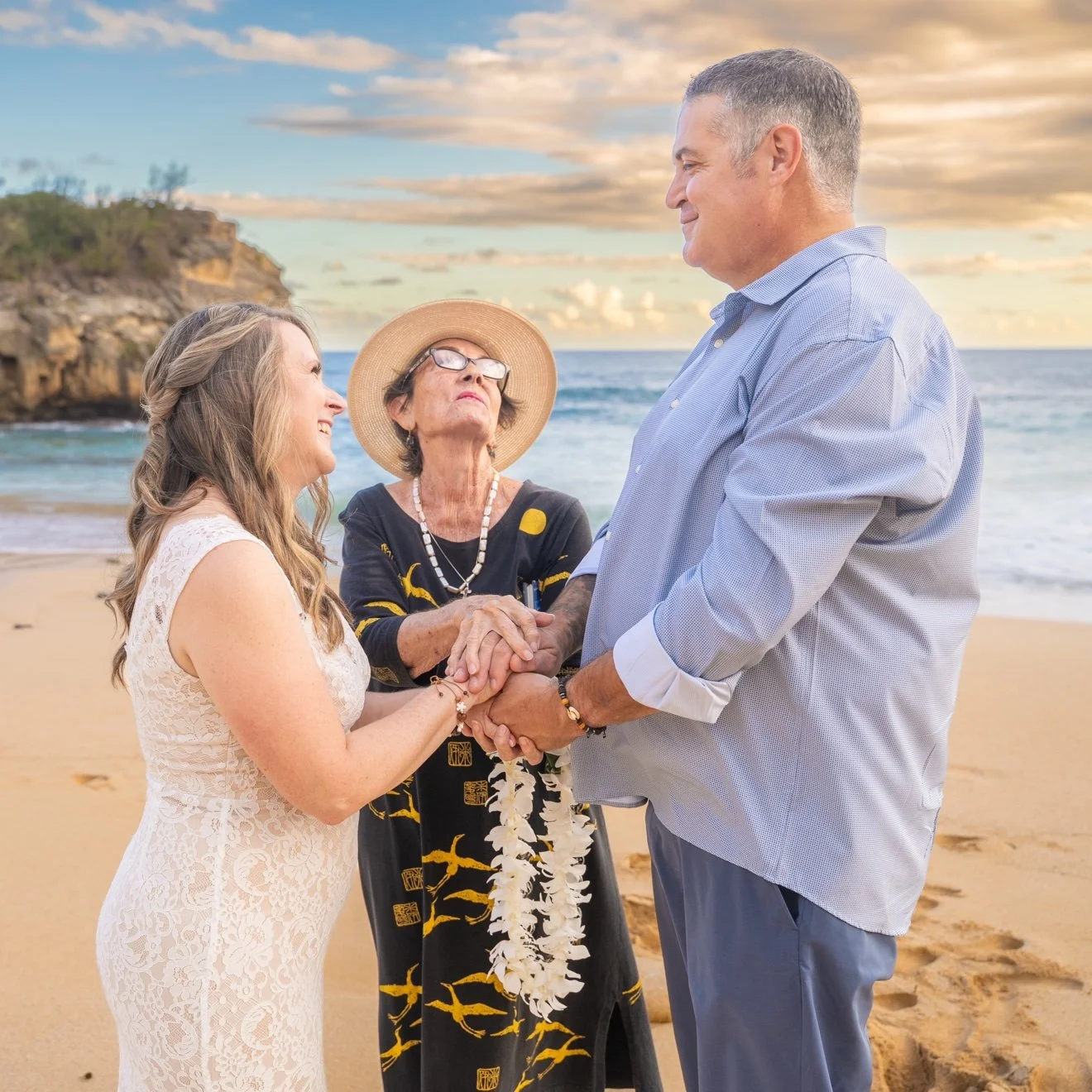 Officiant blessing a bride and groom's joined hands during an intimate beach wedding ceremony on Kauai.