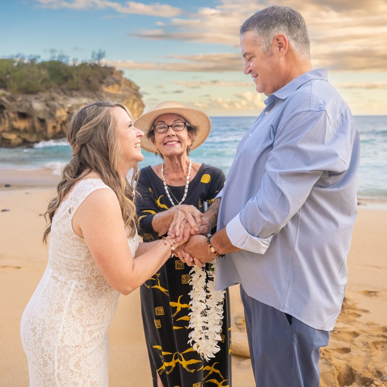 Bride laughing with joy as she and her groom stack hands with their officiant during their Kauai beach wedding ceremony.