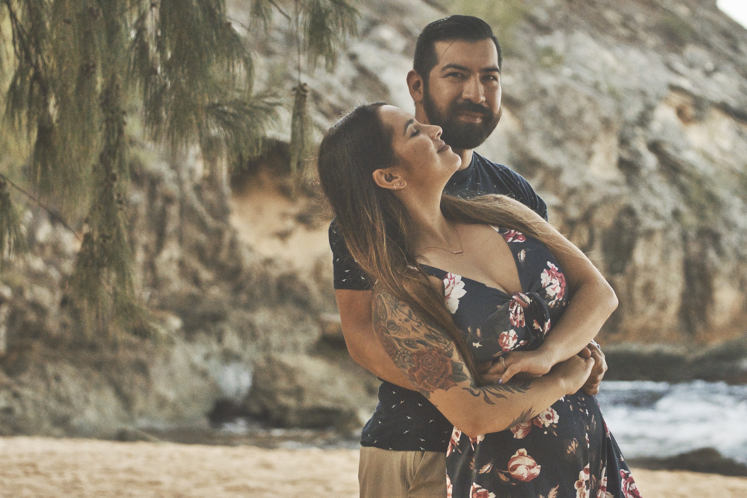 Couple embracing under the trees on the beach at Shipwreck Beach, Kauai.