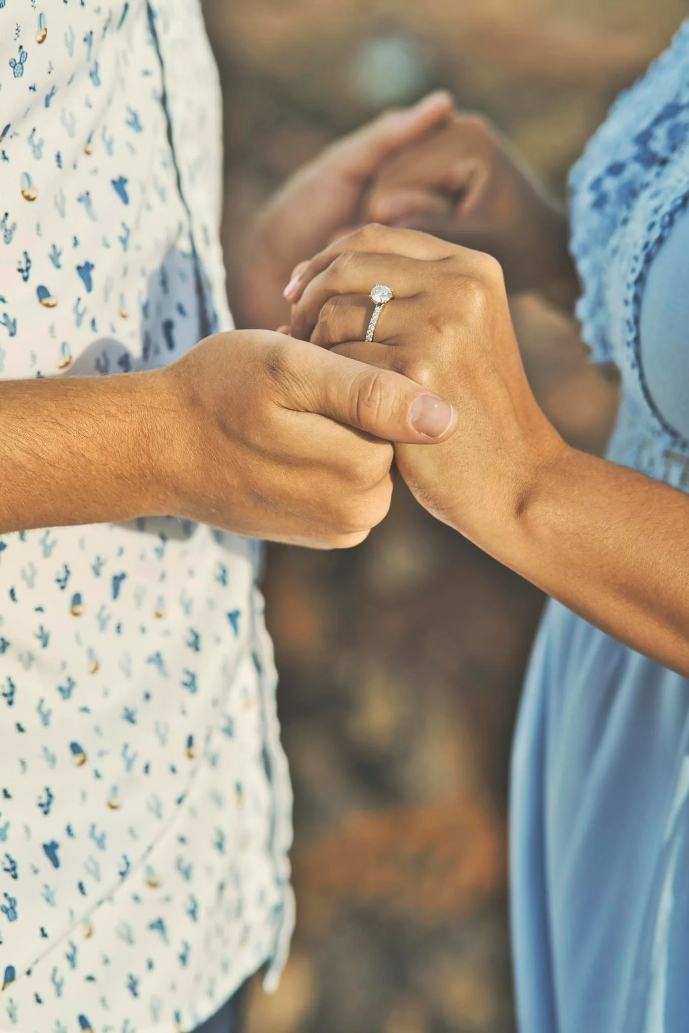 Close-up of a couple holding hands showing an engagement ring on a Kauai beach.
