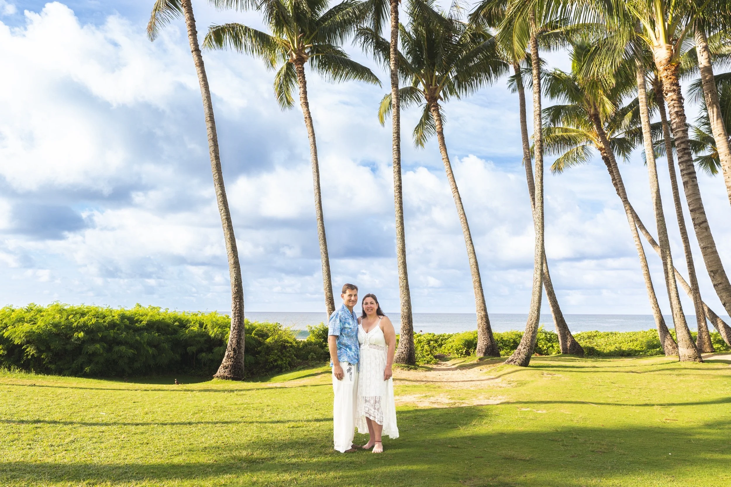 Couple standing together in a palm grove in Kauai.